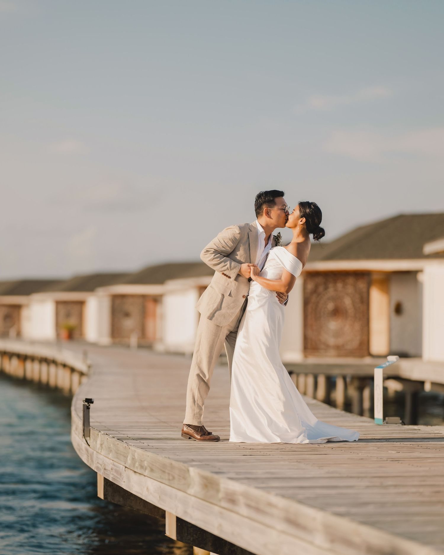 Romantic wedding photos captured on a wooden pier overlooking the ocean.