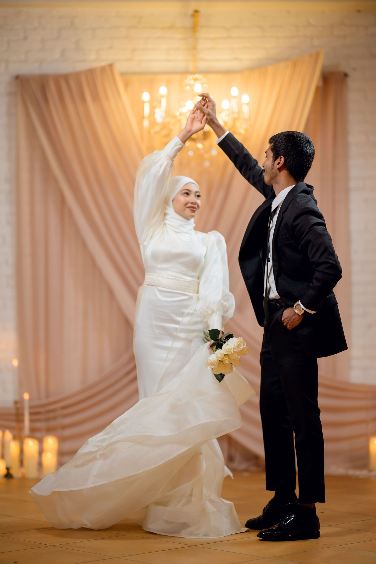 Wedding couple dancing in elegant reception hall with flowing white dress and dramatic lighting.