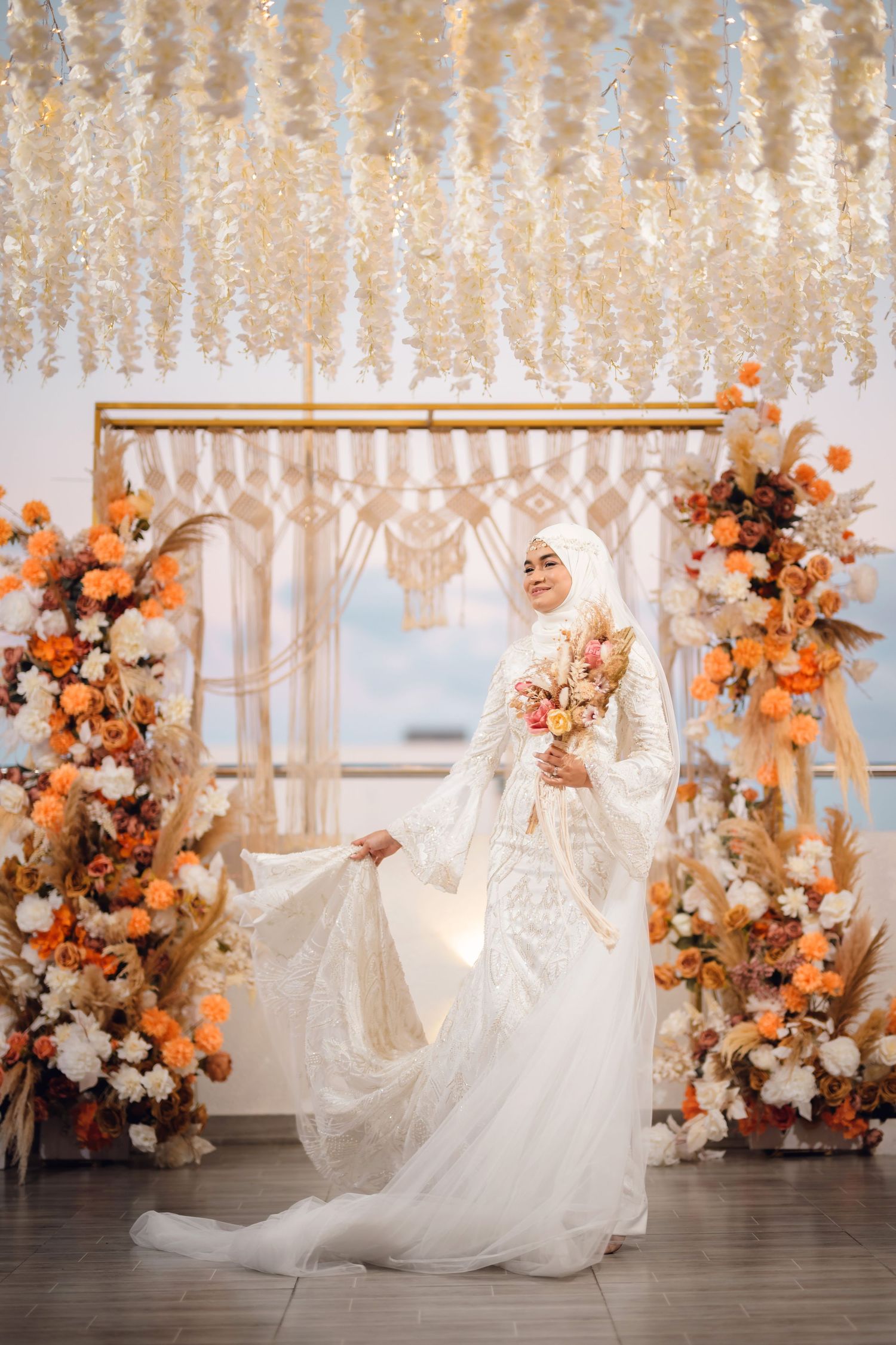 Wedding scene with cascading floral decor featuring orange and white blooms against an elegant white backdrop.