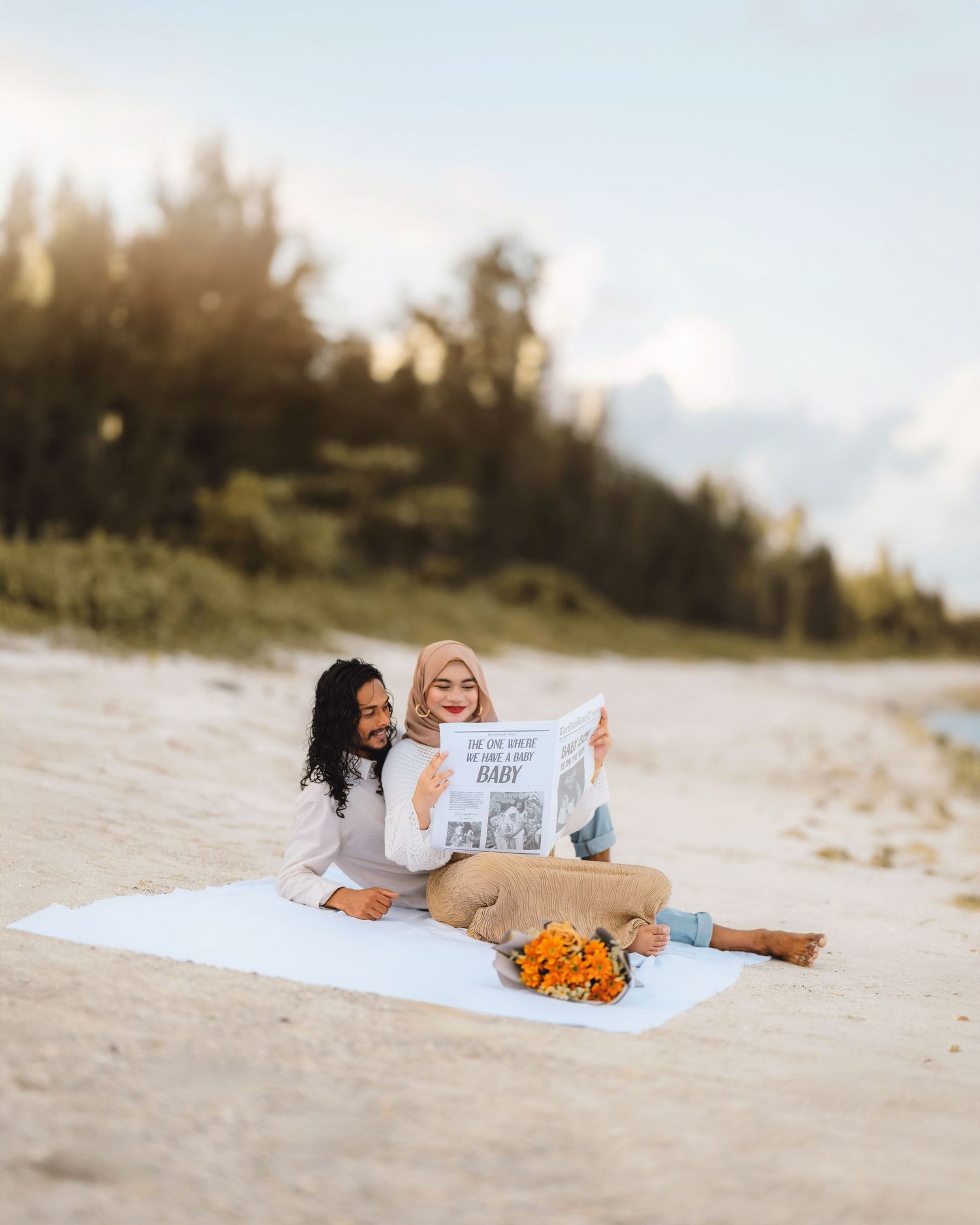 Friends relaxing on beach blanket while reading signs and sharing laughter.