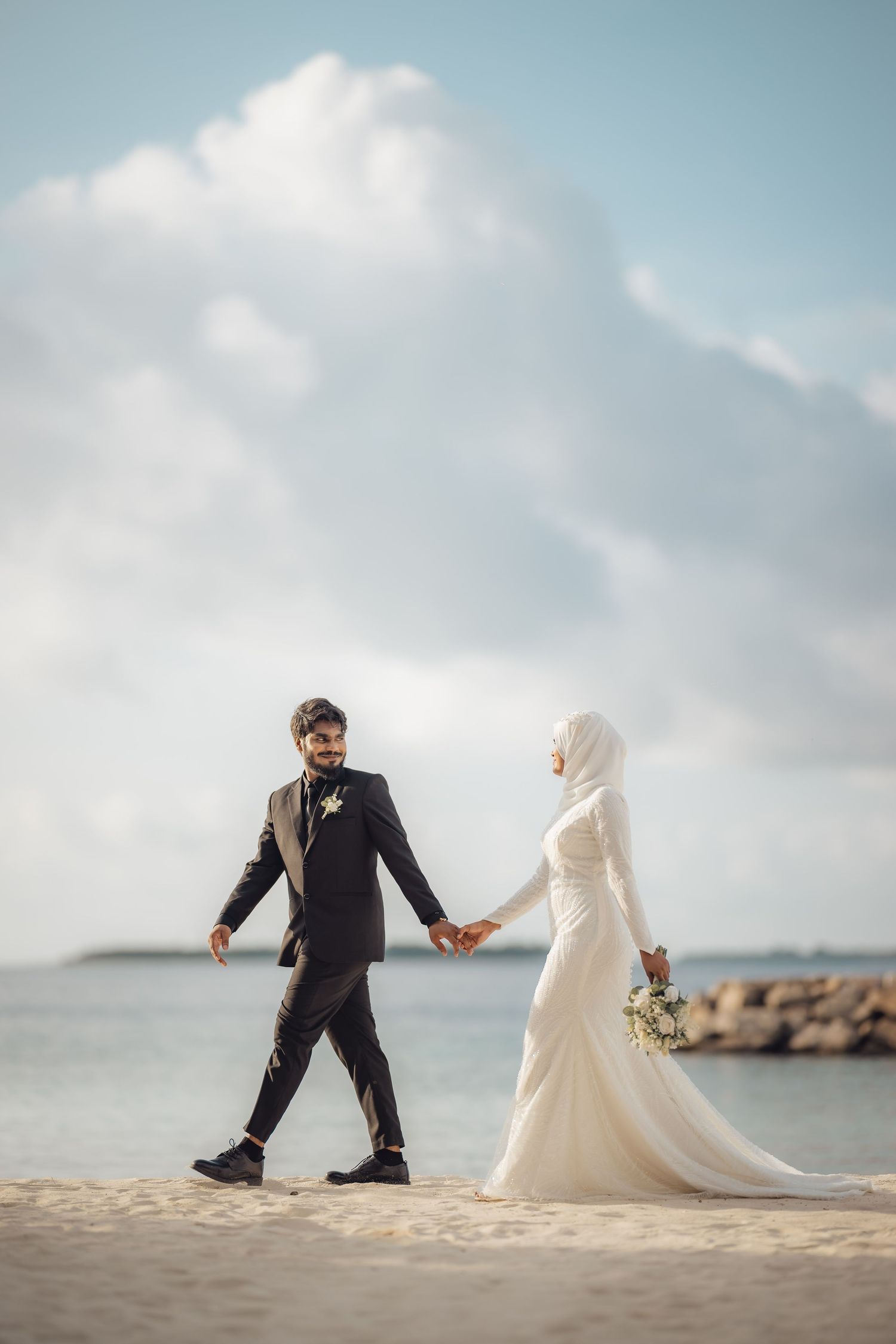 Playful beach wedding photography sequence with couple posing on sandy shore.