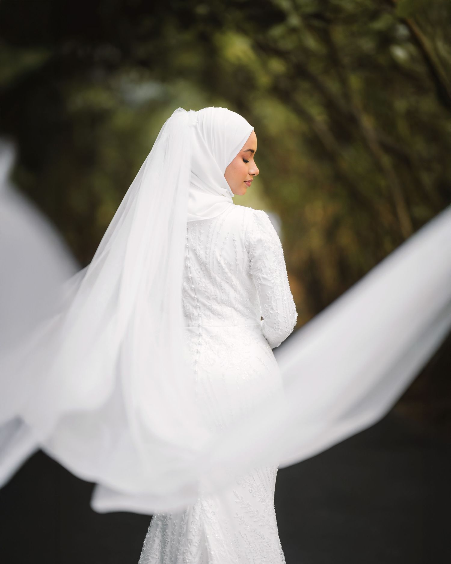 Flowing white wedding dress and veil captured in an artistic spinning motion outdoors.