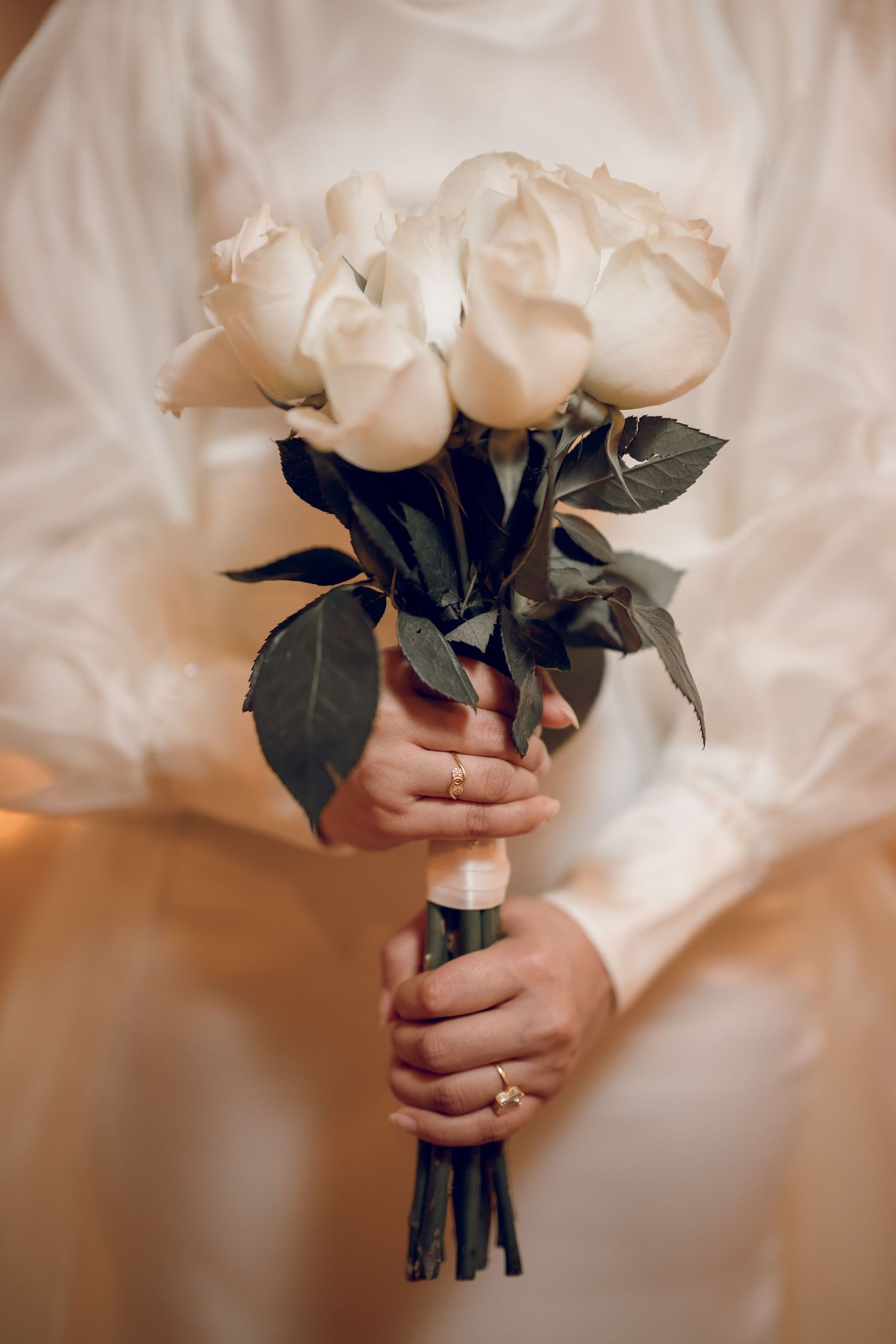 Close-up sequence of white roses bouquet held against white fabric.