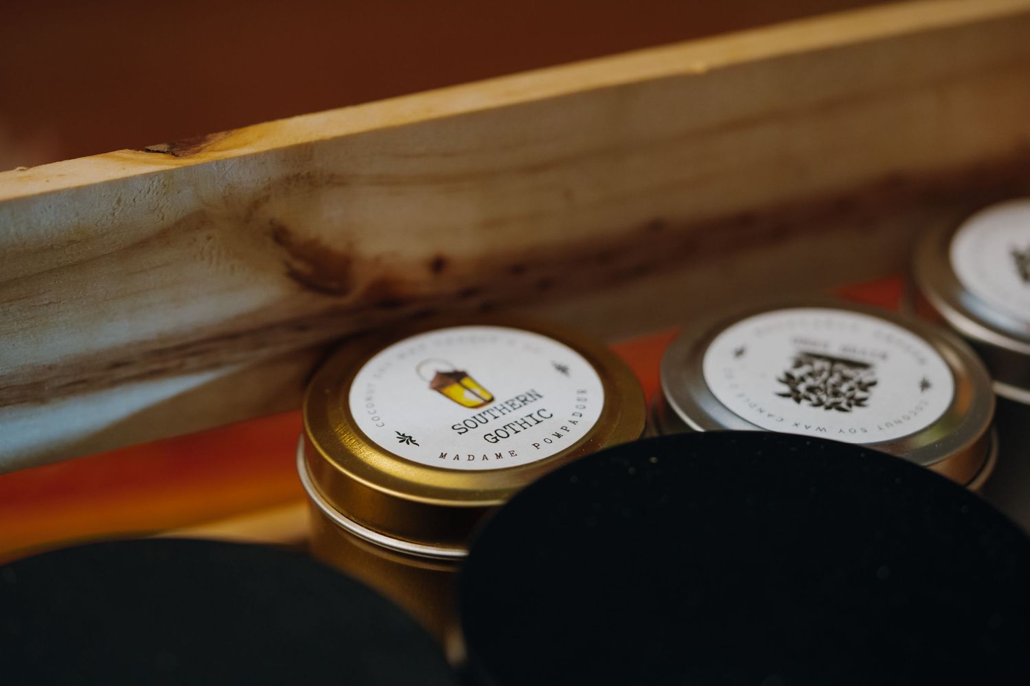 Small gold tin candles with labels stored in a wooden box.