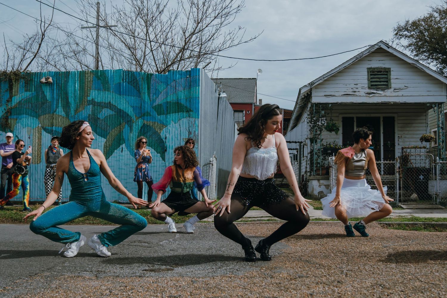 Group of women performing synchronized dance moves outdoors on a residential street.