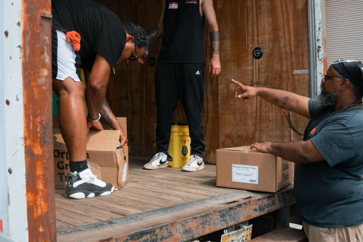 Volunteers unloading and organizing cardboard boxes from a delivery truck at a community event.