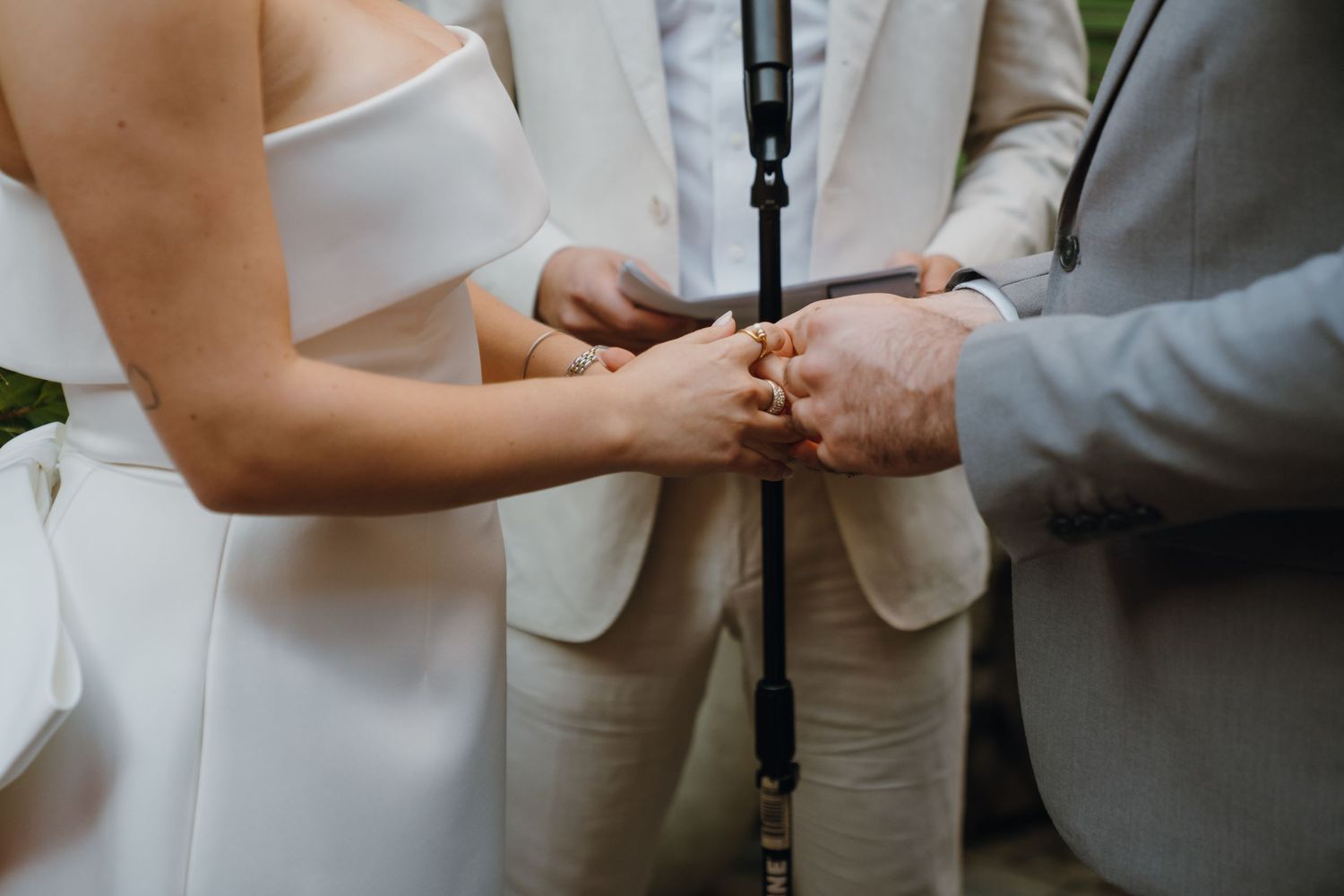 Close-up of officiant joining hands of bride in white dress and groom in gray suit at wedding ceremony. New Orleans, Louisiana, Mississippi