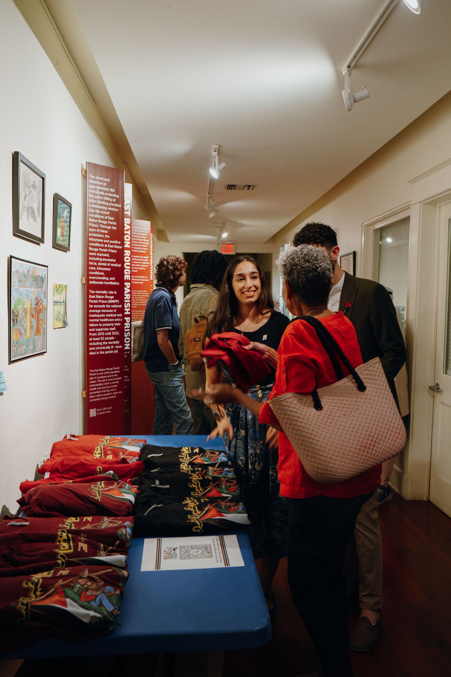 Attendees browse red merchandise at a community event display table.