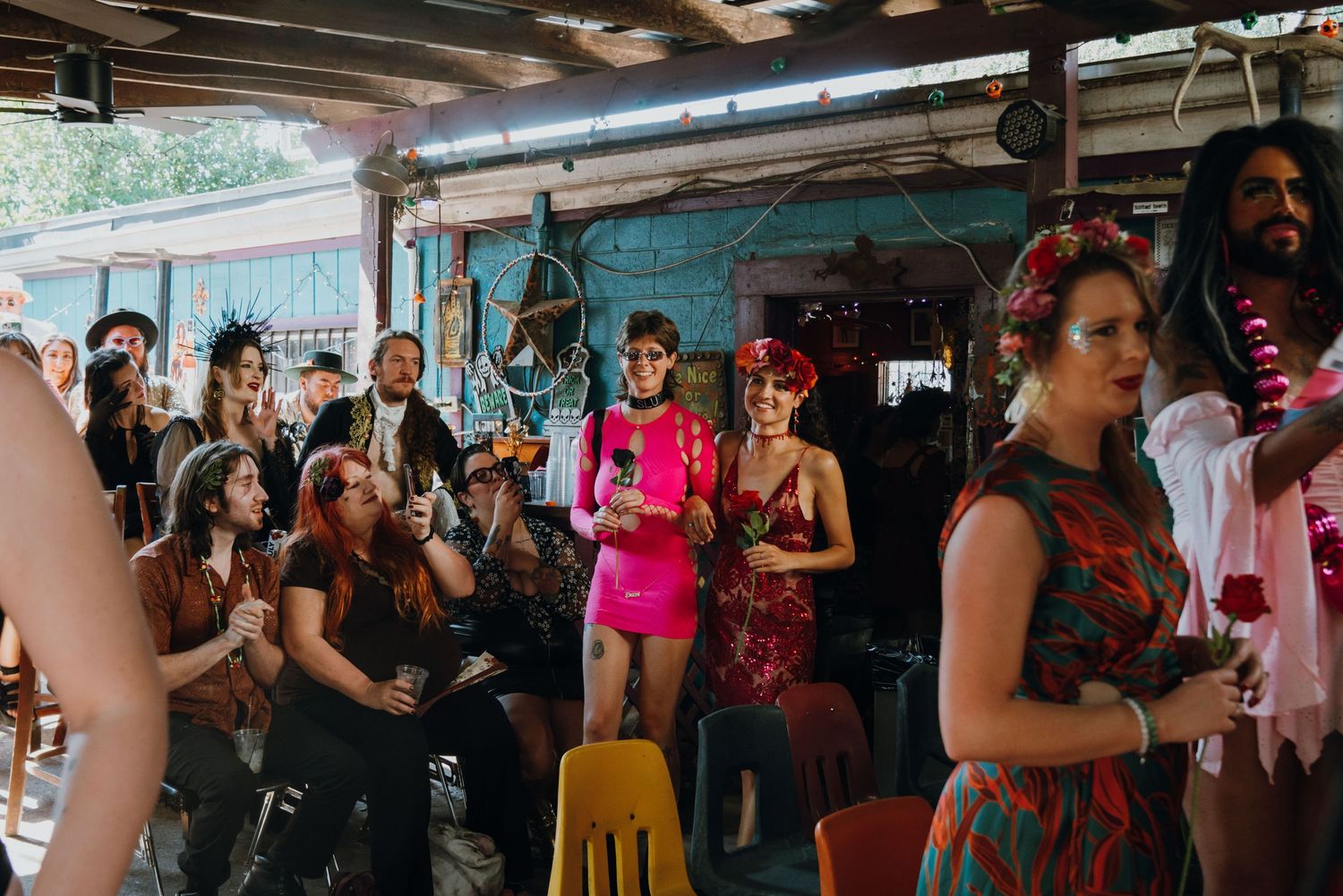 Colorful crowd of guests in festive costumes gathered at an eclectic indoor bar venue for a vibrant celebration.