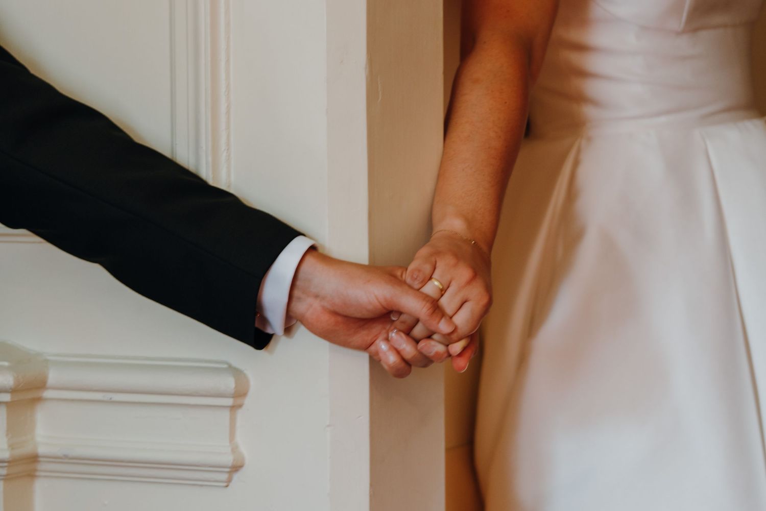Close-up of bride and groom holding hands, showcasing wedding rings and elegant attire. New Orleans, Louisiana, Mississippi