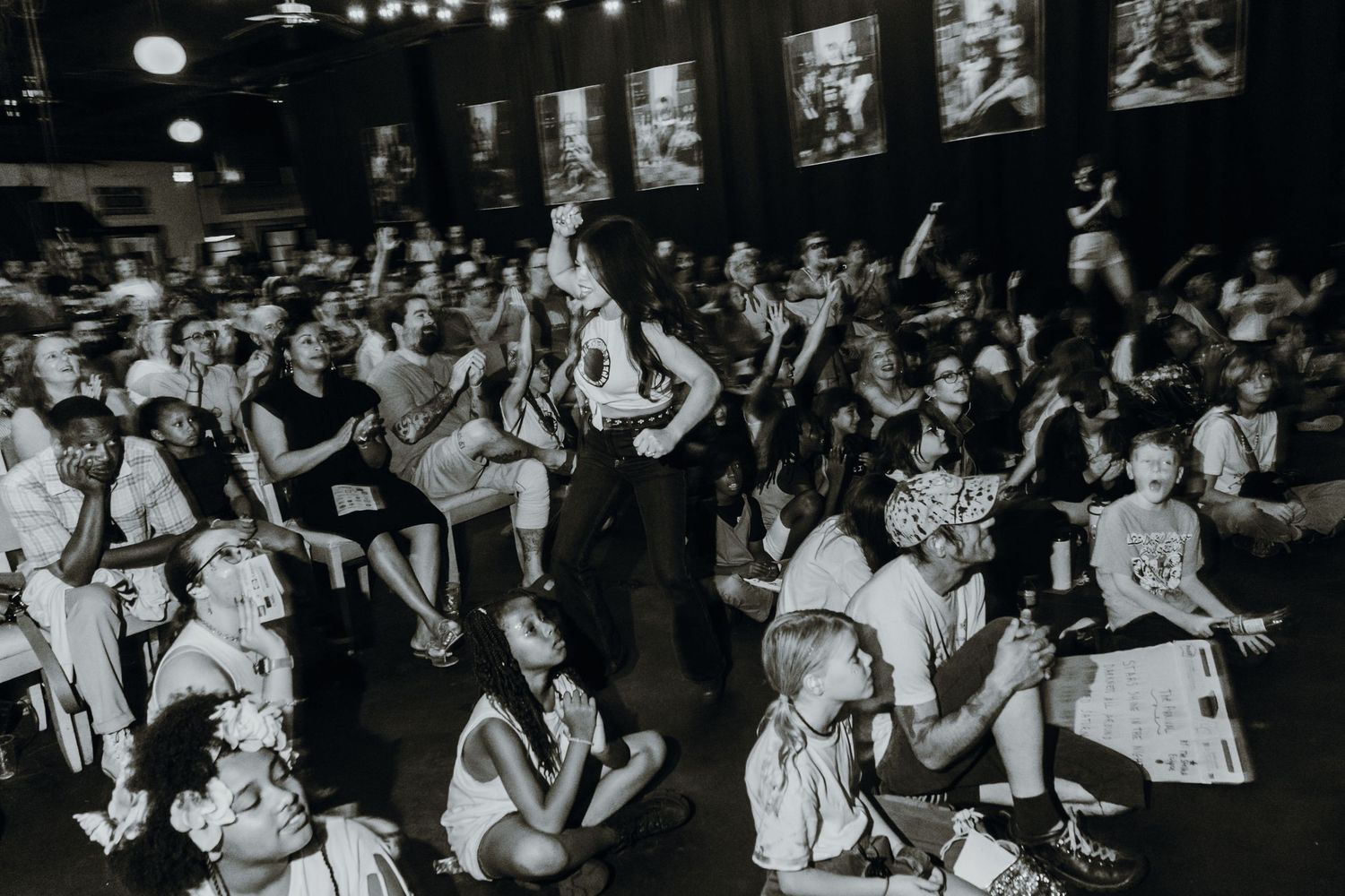 Black and white photo of an enthusiastic crowd enjoying a live music performance indoors.