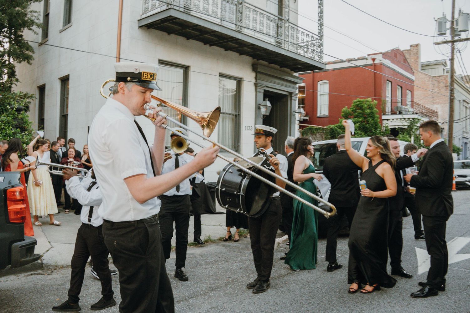 New Orleans second line wedding parade with brass band trombone player leading guests down street.