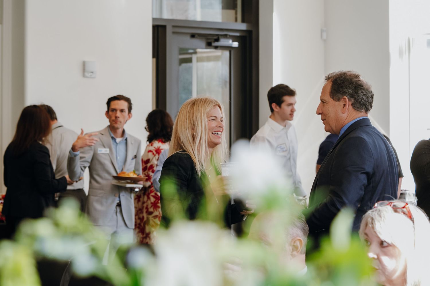 Professionals mingling at an elegant indoor networking reception with floral arrangements.