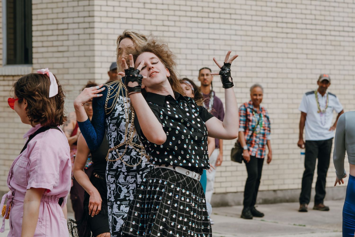 Woman in polka dot dress dancing expressively outdoors at a street performance event.