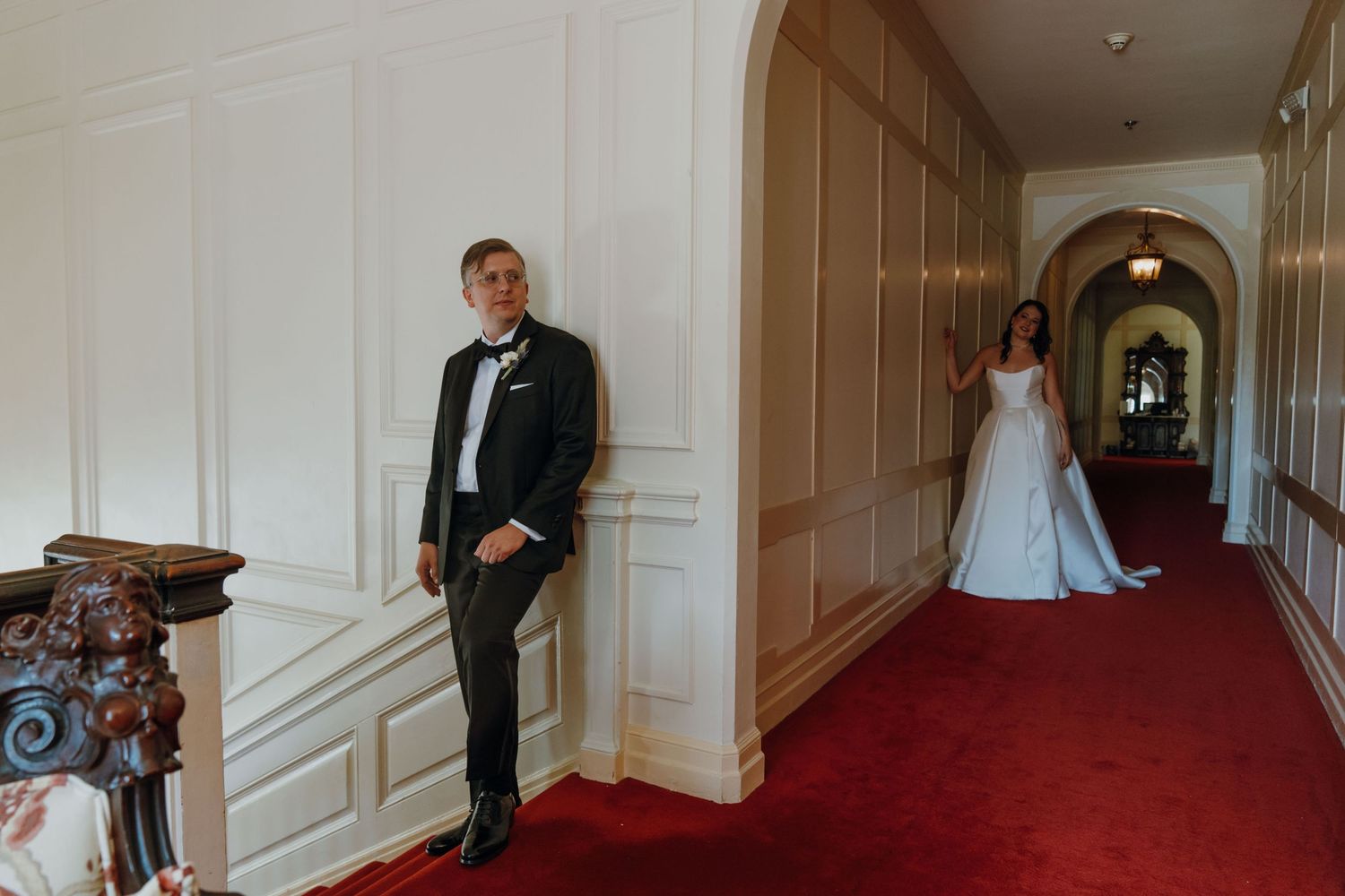 Bride in white gown and groom in black tuxedo sharing a first look moment in an elegant hallway. New Orleans, Louisiana, Mississippi