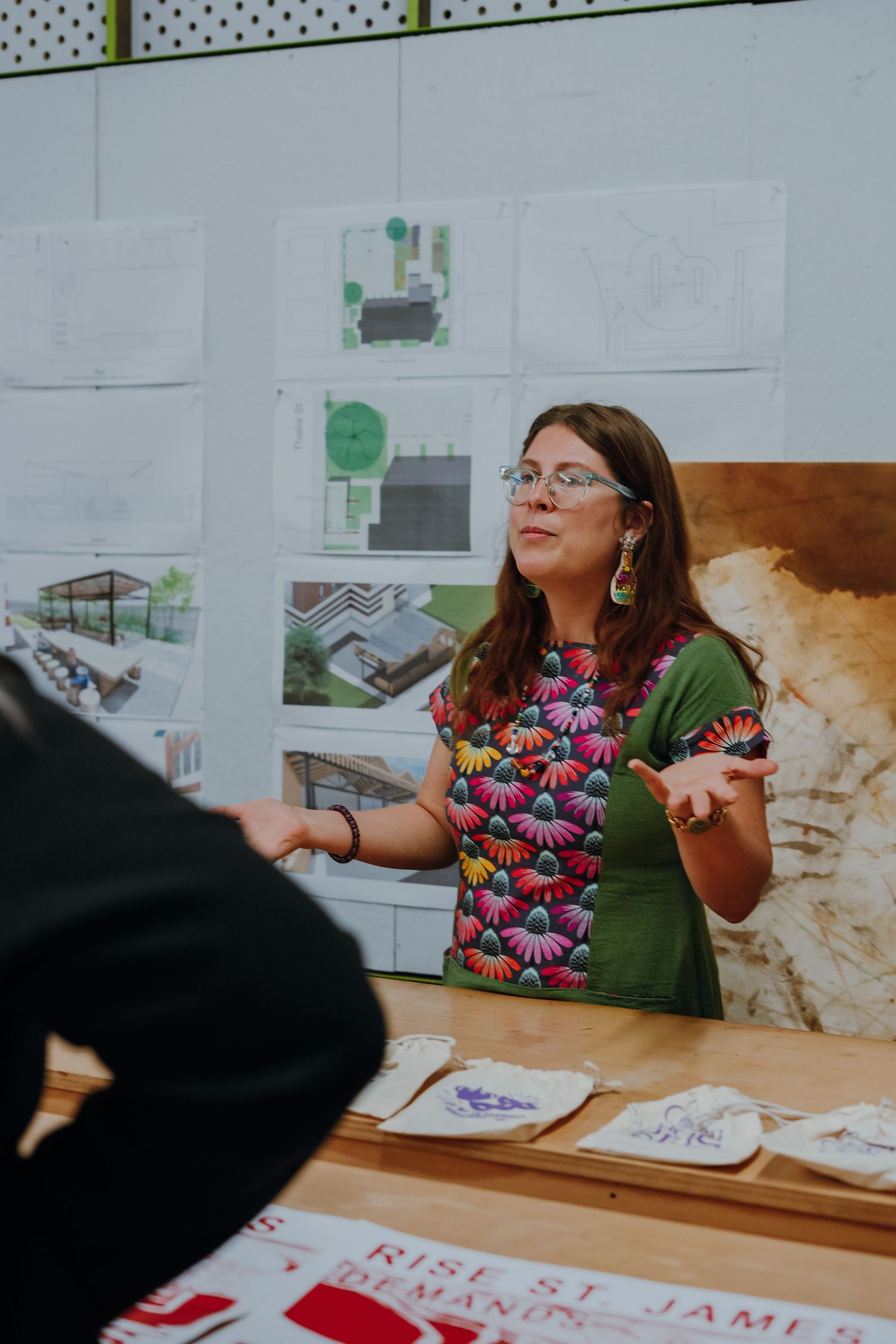 Woman in floral dress presenting architectural designs at a Rise St. James community planning workshop.