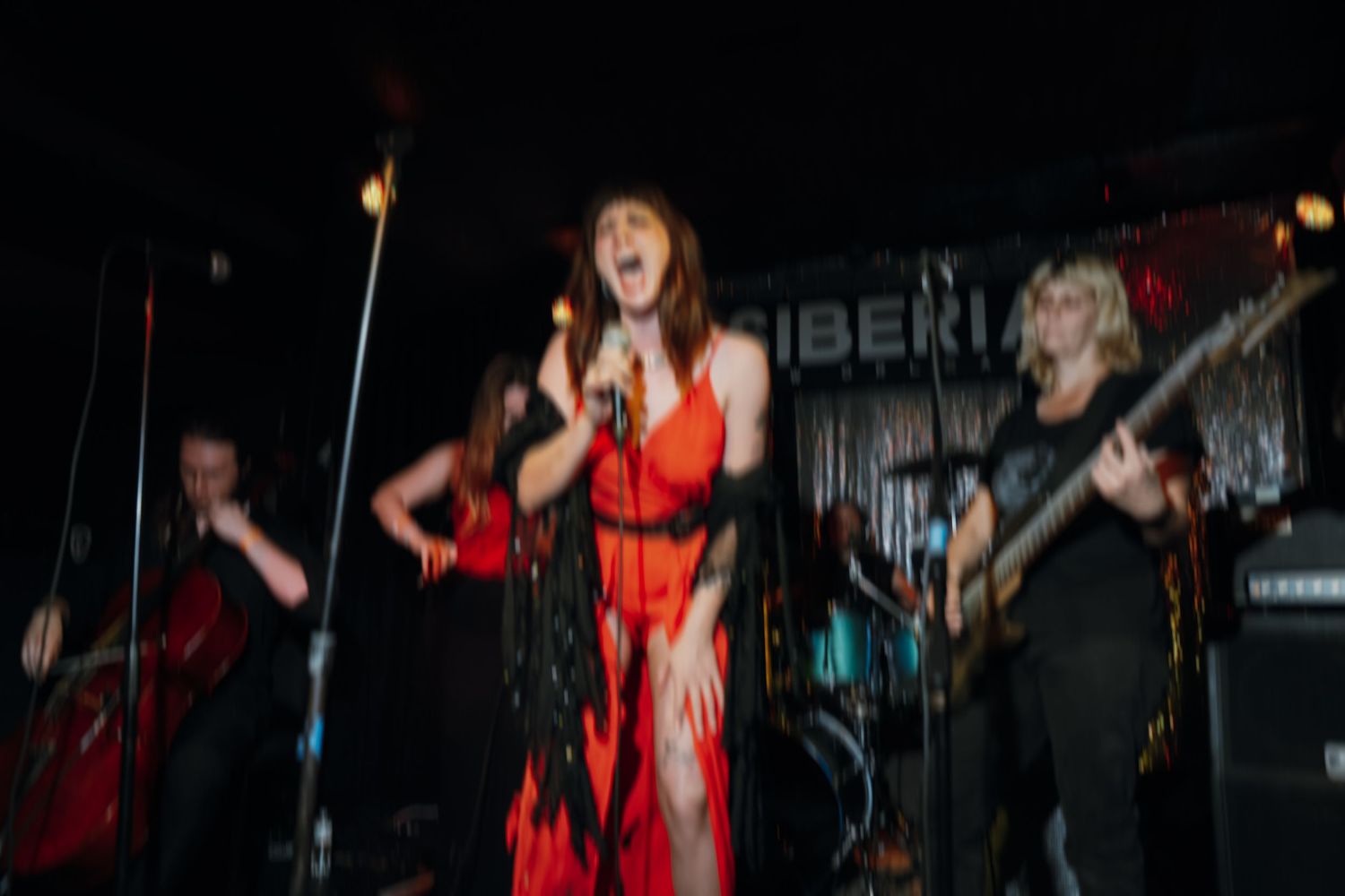 Female vocalist in red dress performing energetically on stage at Siberia New Orleans with band.