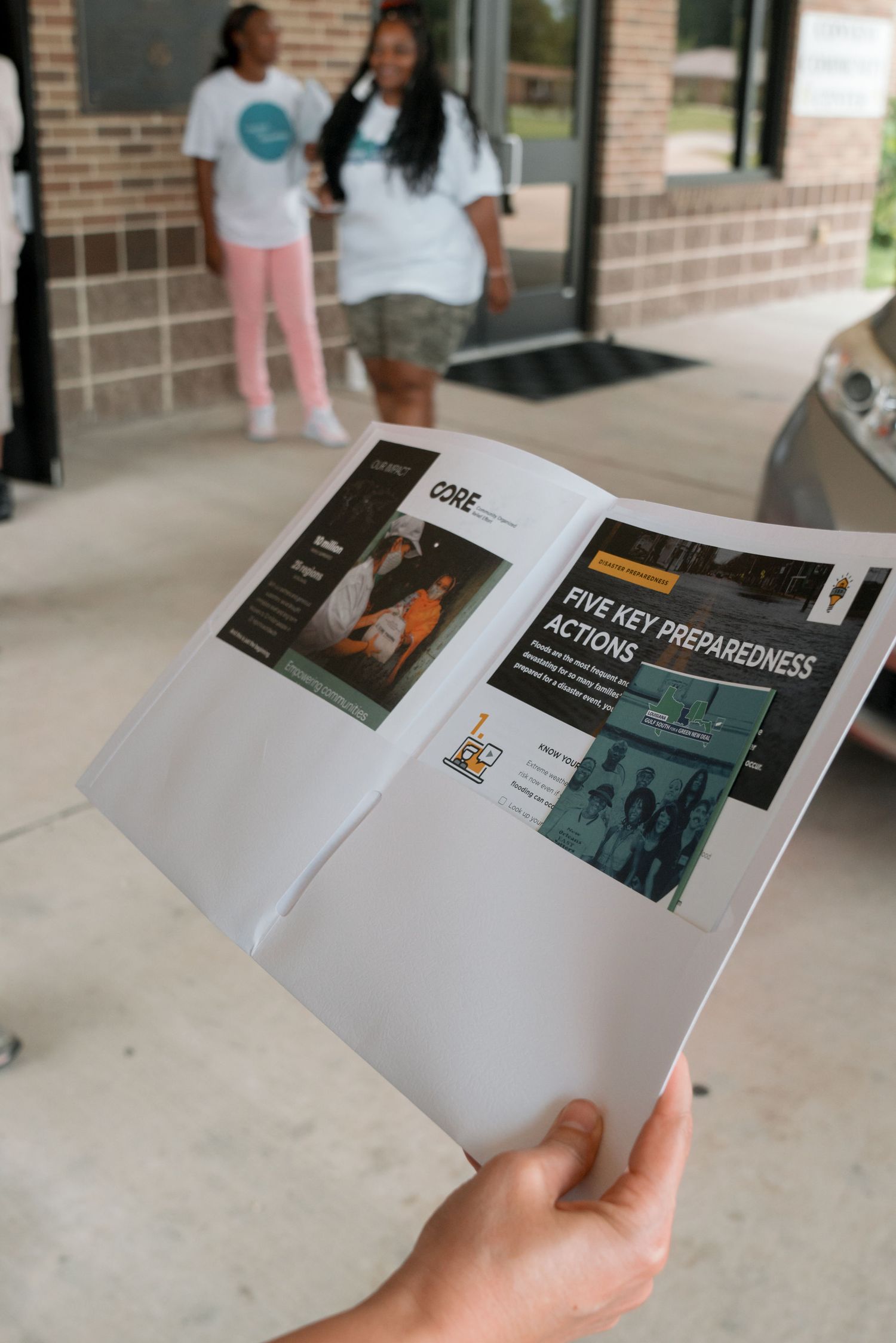 Hand holding a CORE newsletter featuring Five Key Preparedness Actions outside a building.