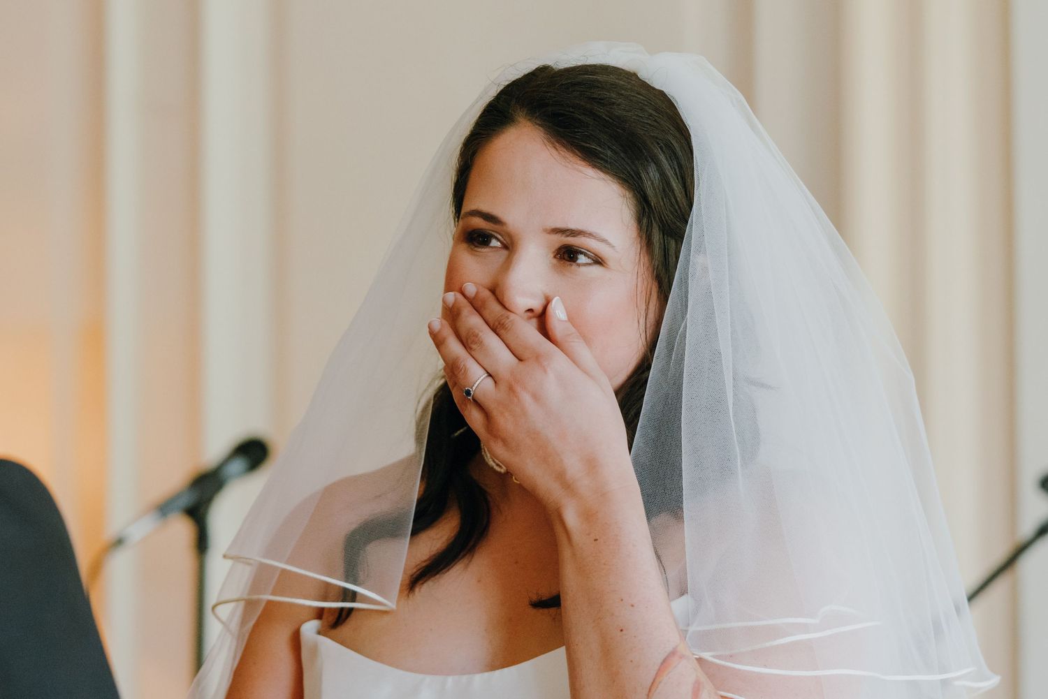 Emotional bride in white veil covering her mouth with hand during wedding ceremony. New Orleans, Louisiana, Mississippi