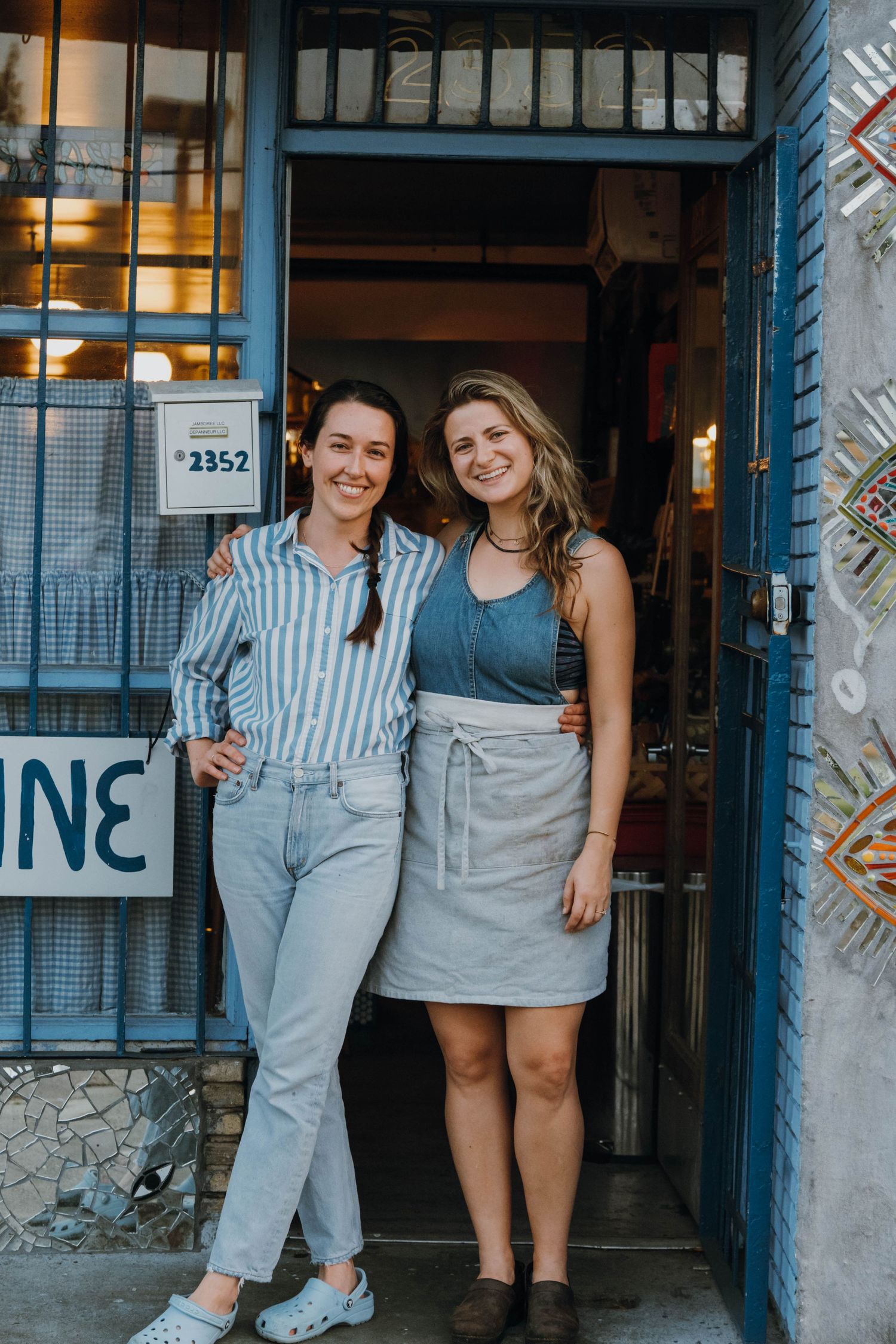 Two smiling women posing together in the doorway of a restaurant with blue trim.