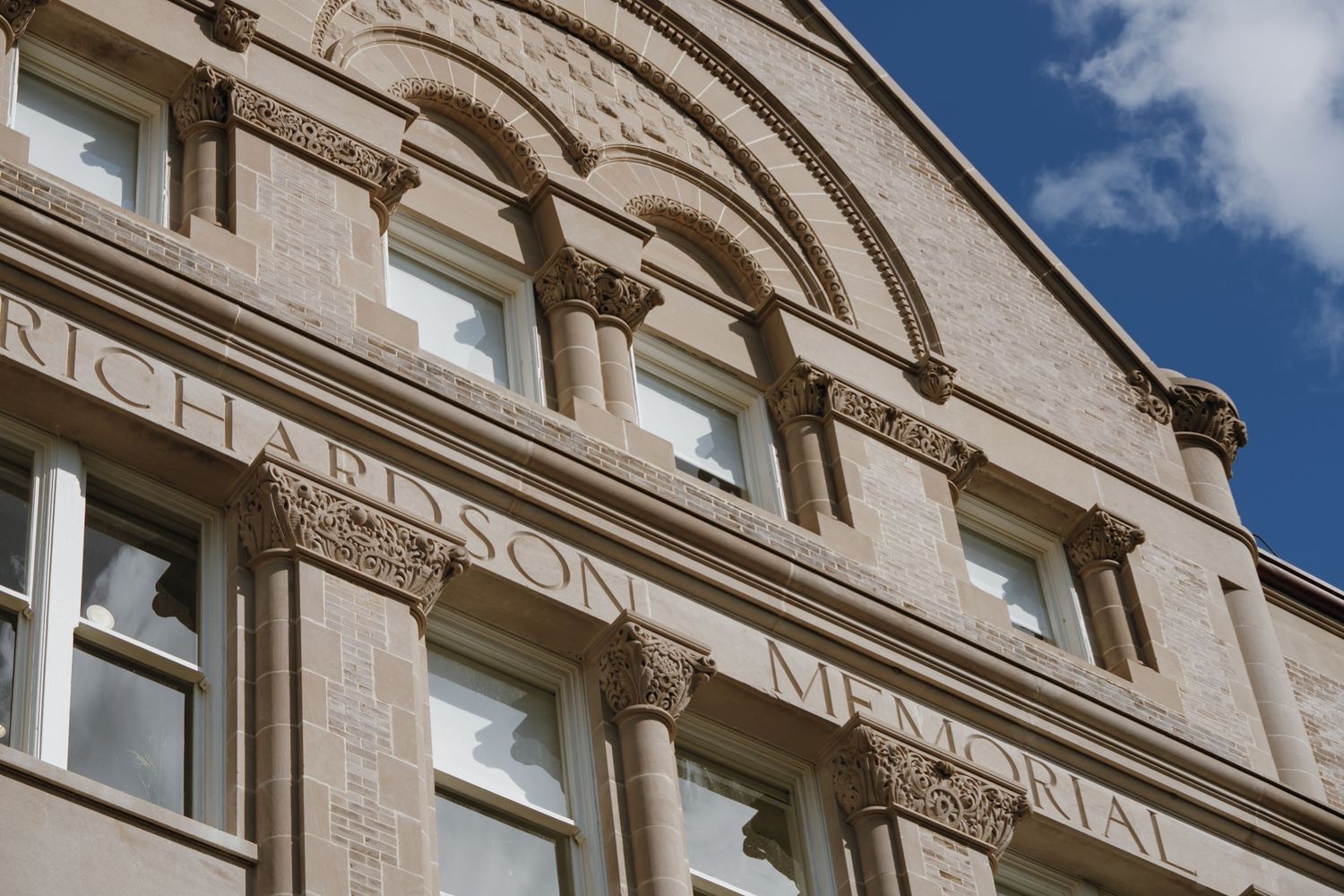 Historic Richardson Memorial building facade with ornate stone carvings against a blue sky.