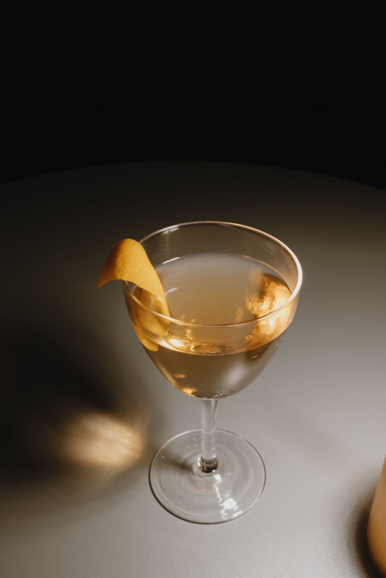 A classic martini cocktail garnished with a citrus peel twist in an elegant coupe glass on a dark background.