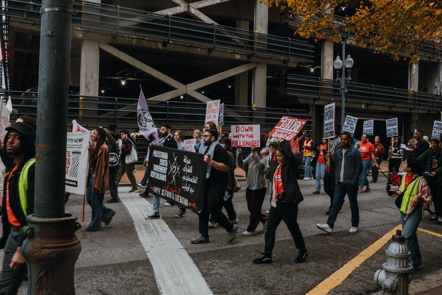 Protesters march down an urban street carrying signs and banners during a public demonstration.