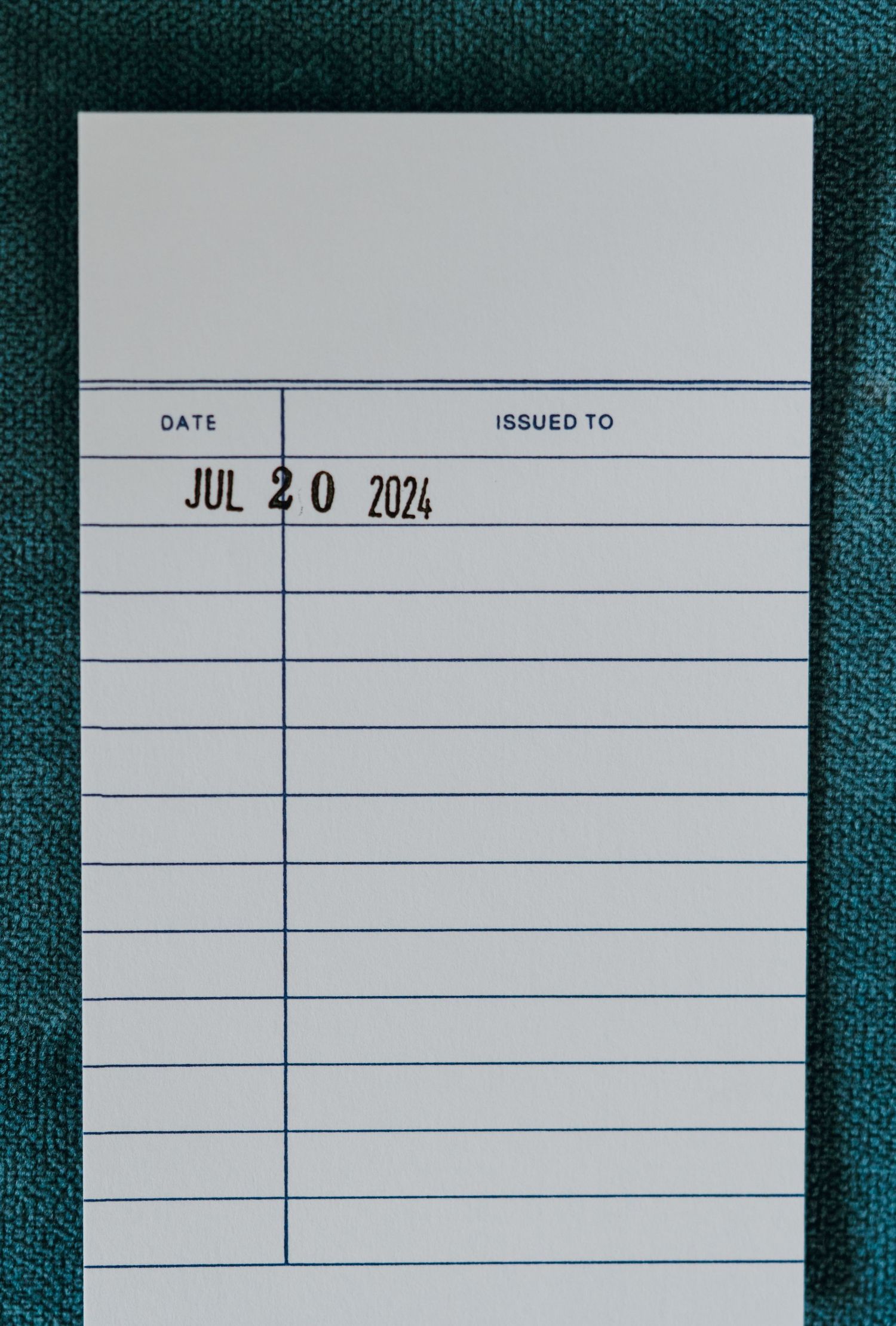 Library card stamped with date JUL 20 2024 on teal fabric background. New Orleans, Louisiana, Mississippi