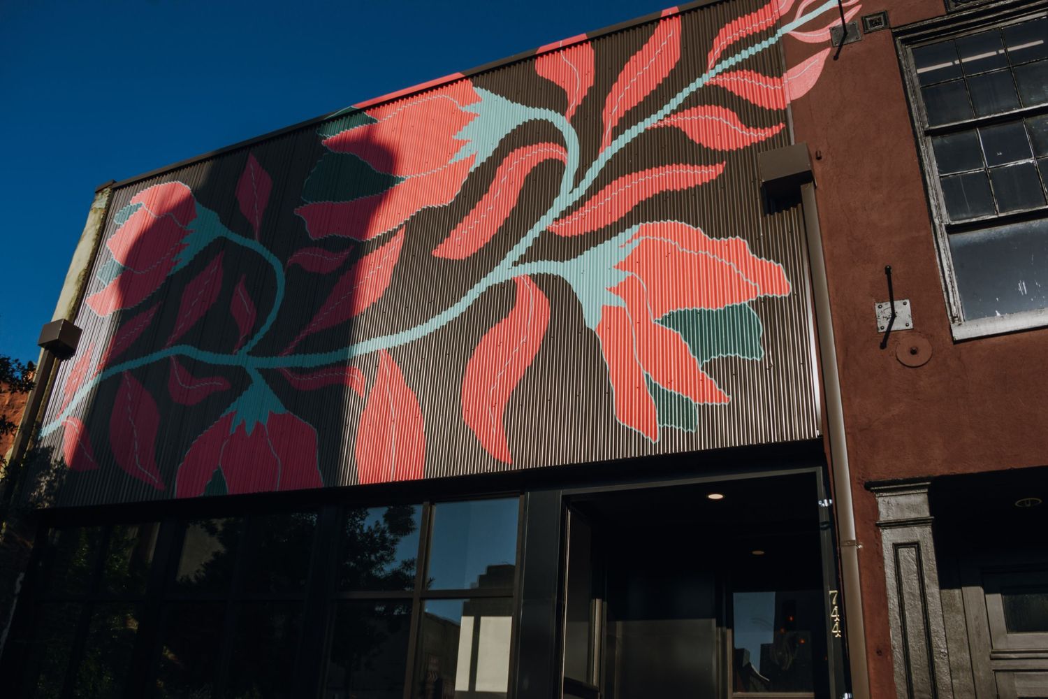 Vibrant large-scale floral mural with red and pink botanical design on exterior of urban wedding venue. New Orleans, Louisiana, Mississippi
