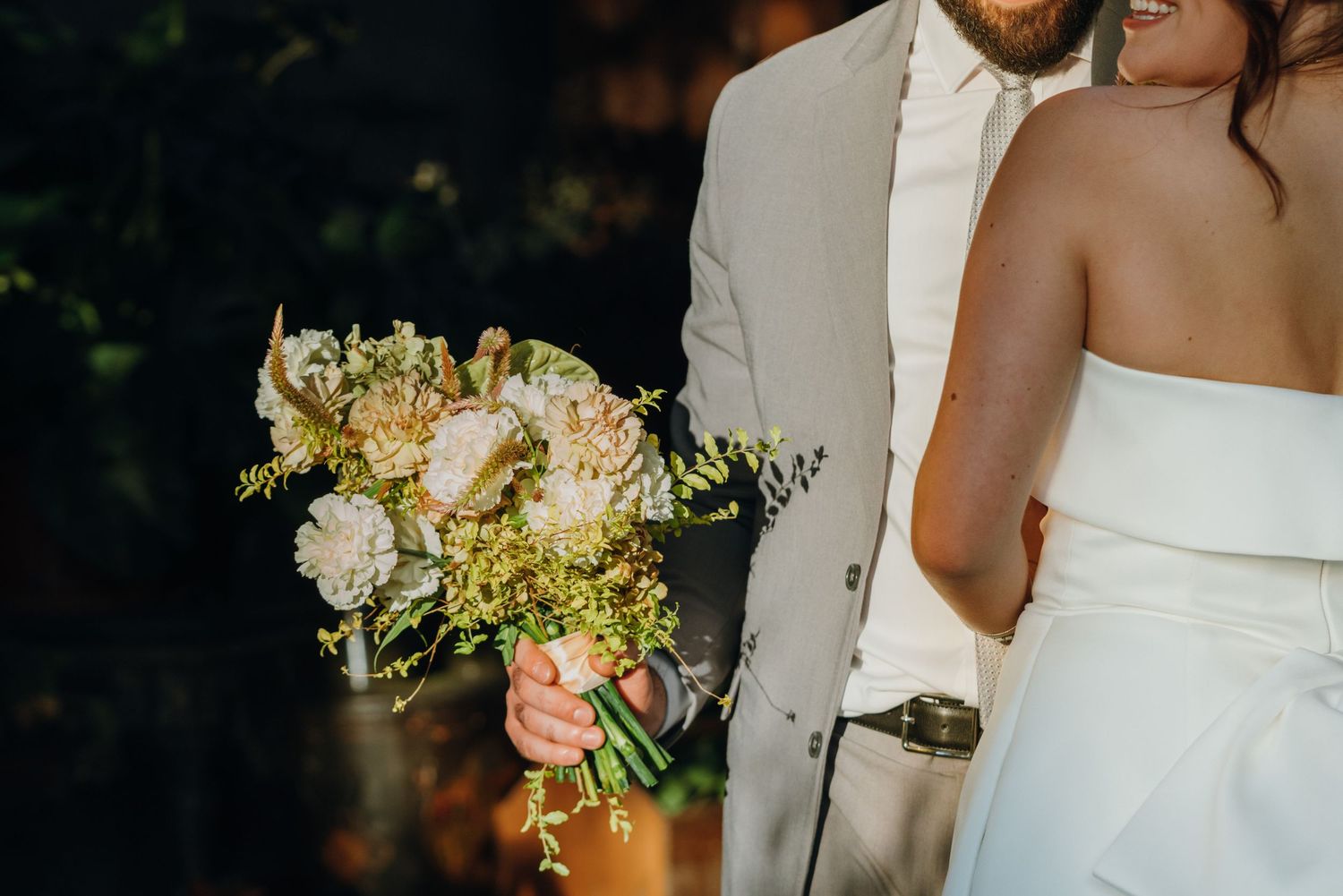 Close-up of groom holding elegant bridal bouquet with white peonies and wildflowers at outdoor wedding. New Orleans, Louisiana, Mississippi