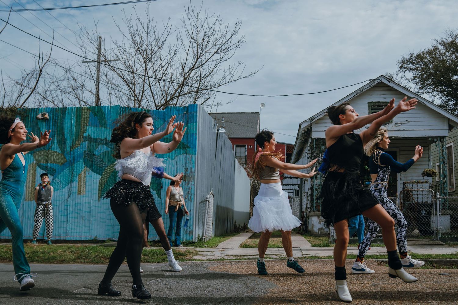 Group of women performing expressive outdoor street dance with arms extended.