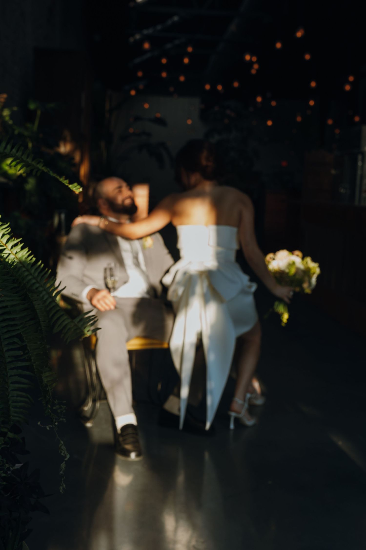 Bride and groom share an intimate moment in dimly lit reception venue with string lights and ferns. New Orleans, Louisiana, Mississippi