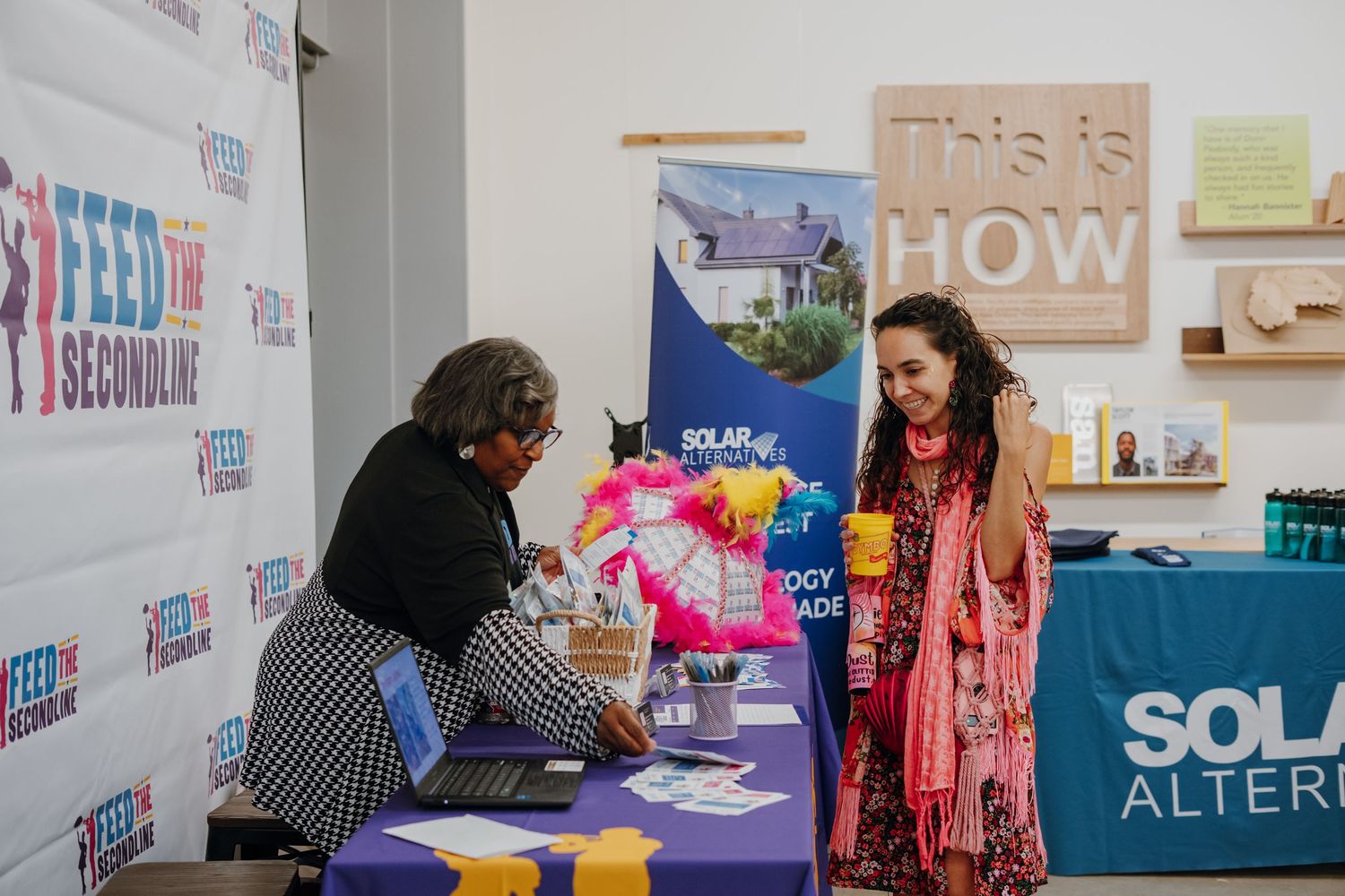 Two women conversing at a Solar Alternatives and Feed the Second Line community event table.