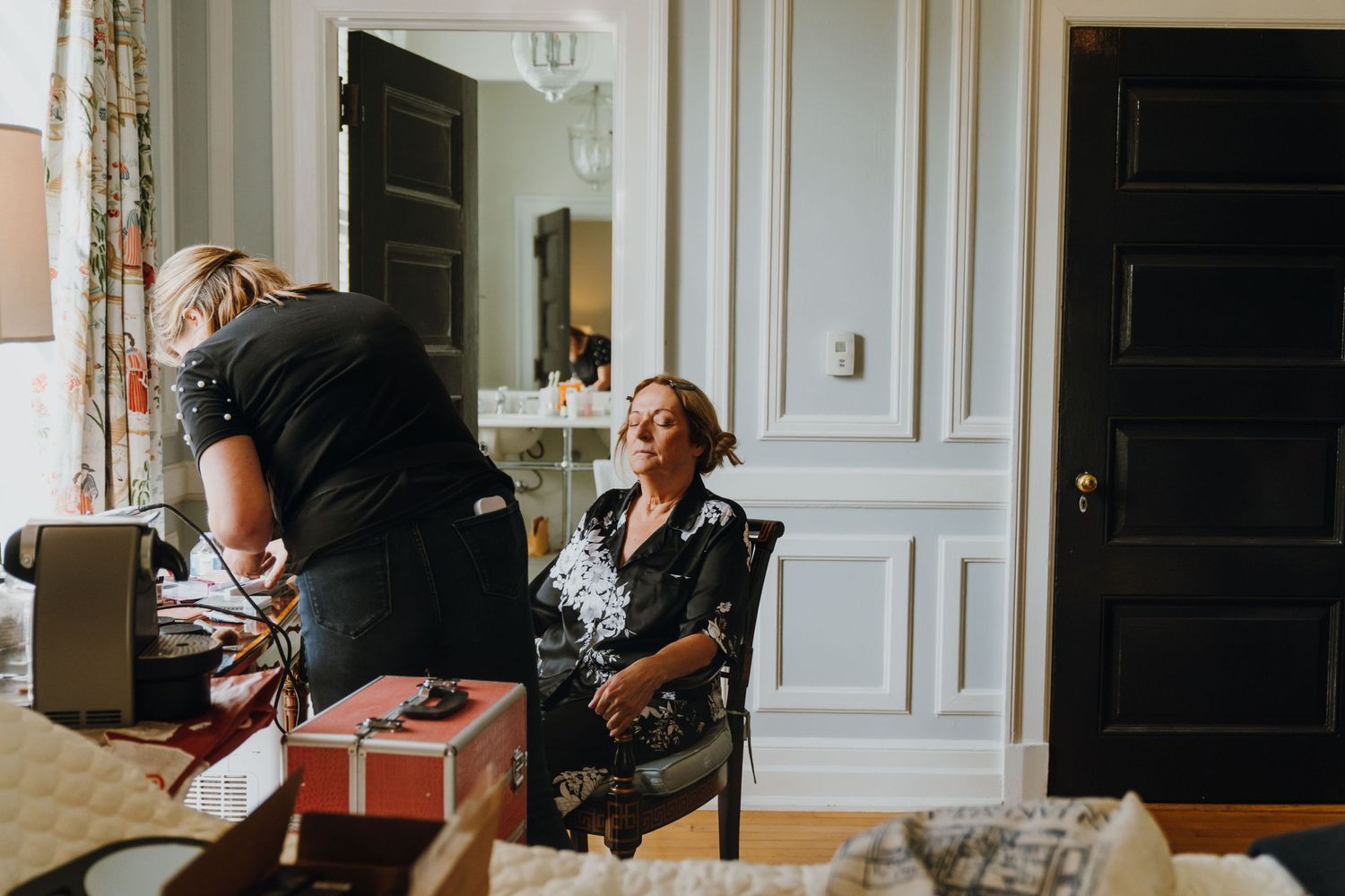Bride sitting in chair getting hair styled by professional hairstylist in elegant white paneled room. New Orleans, Louisiana, Mississippi