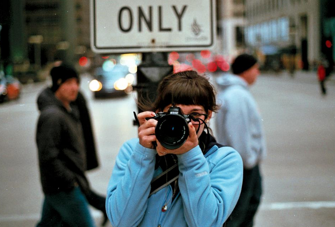 Person in blue hoodie photographing with DSLR camera on busy city street with ONLY sign visible. New Orleans, Louisiana, Mississippi