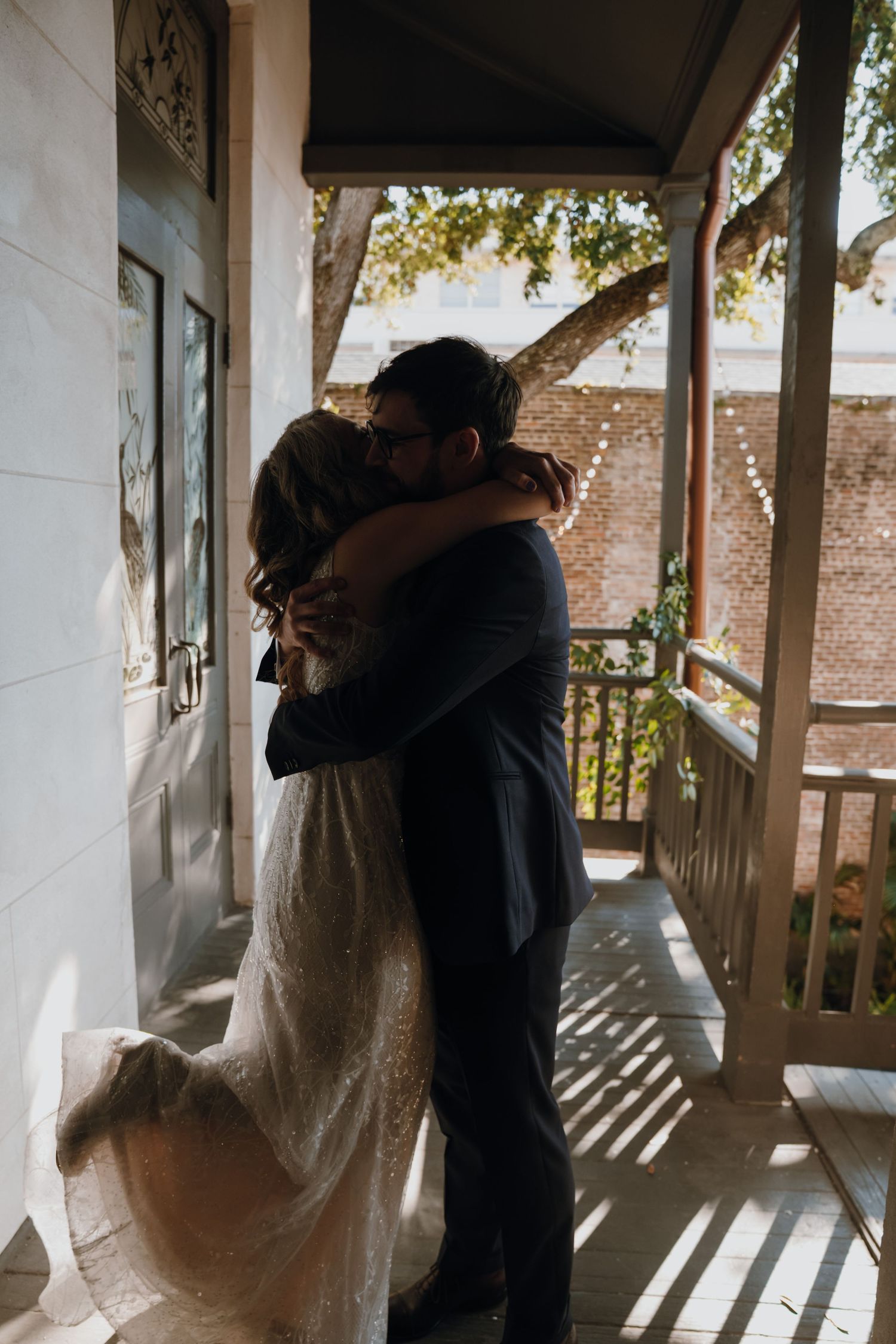 Bride and groom sharing emotional embrace on porch during wedding first look moment.