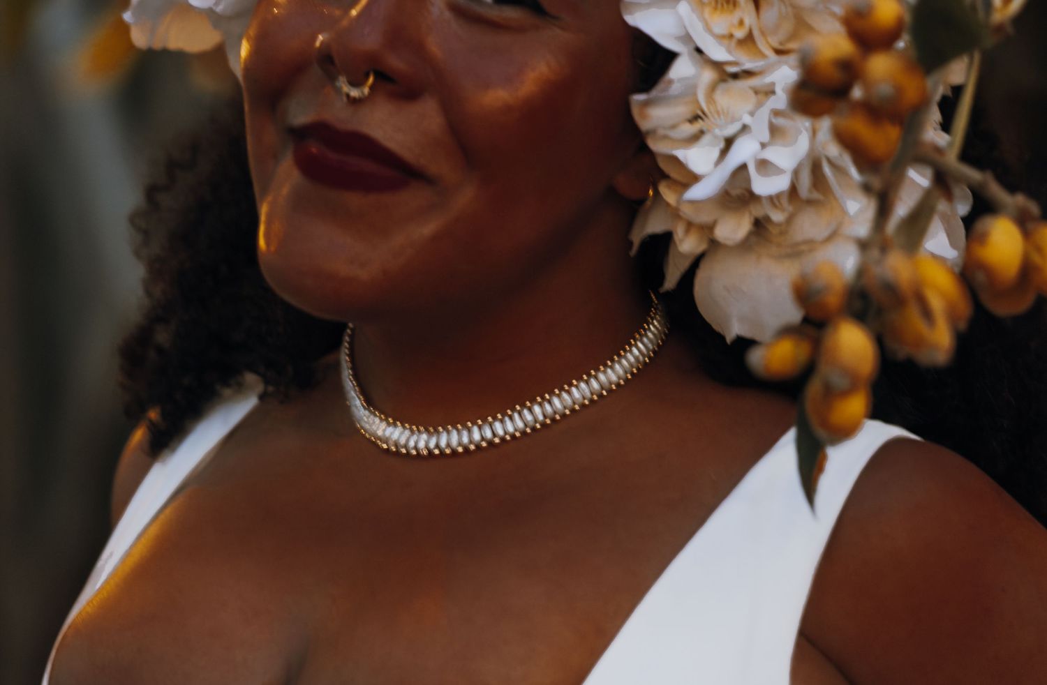 Close-up of bride wearing a diamond choker necklace and white floral hair accessory.