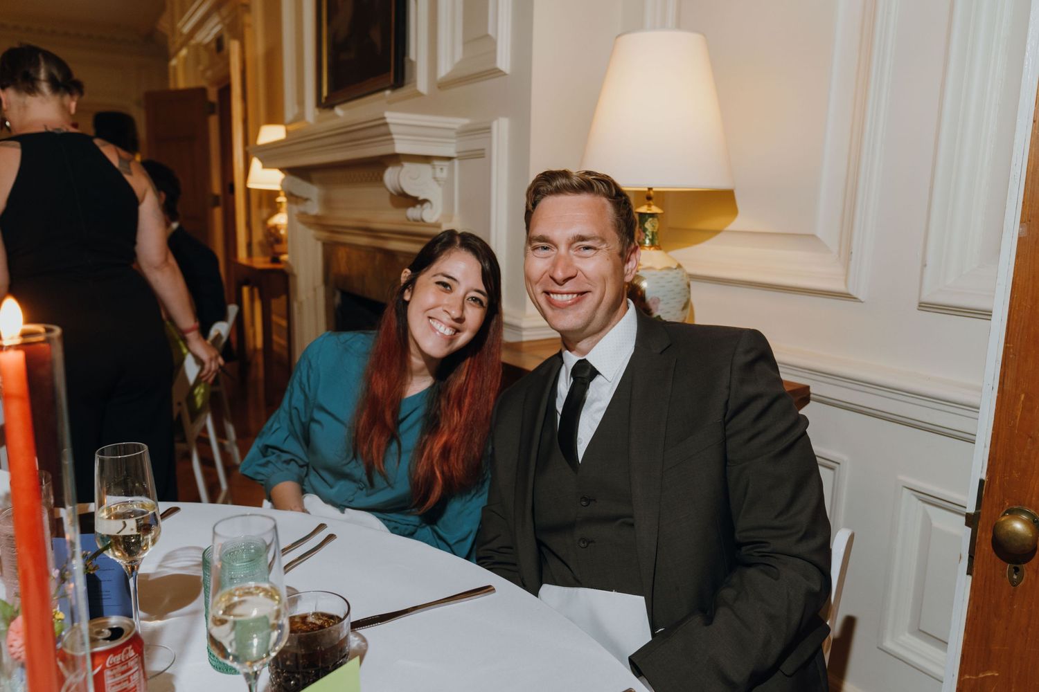 Smiling couple sits together at a wedding reception dinner table in an elegant candlelit room. New Orleans, Louisiana, Mississippi