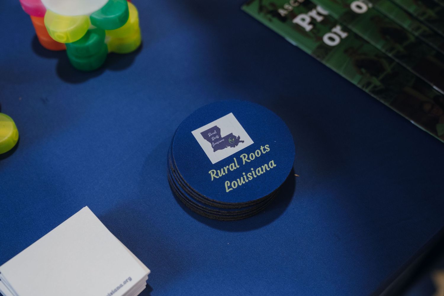 Round blue button badge with Rural Roots Louisiana logo on a blue table surface.