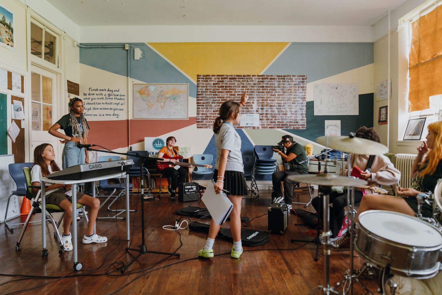 Students rehearse band music together in colorful classroom with keyboard, drums, and guitars. New Orleans, Louisiana, Mississippi
