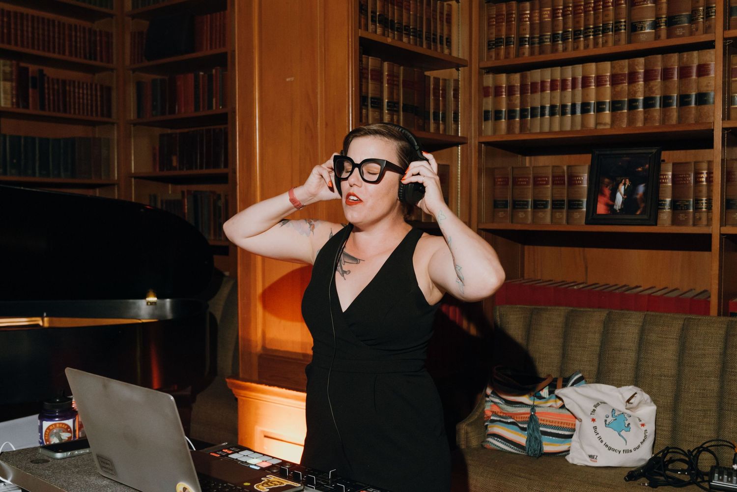 A DJ wearing black dress and headphones performs in a library filled with bookshelves. New Orleans, Louisiana, Mississippi