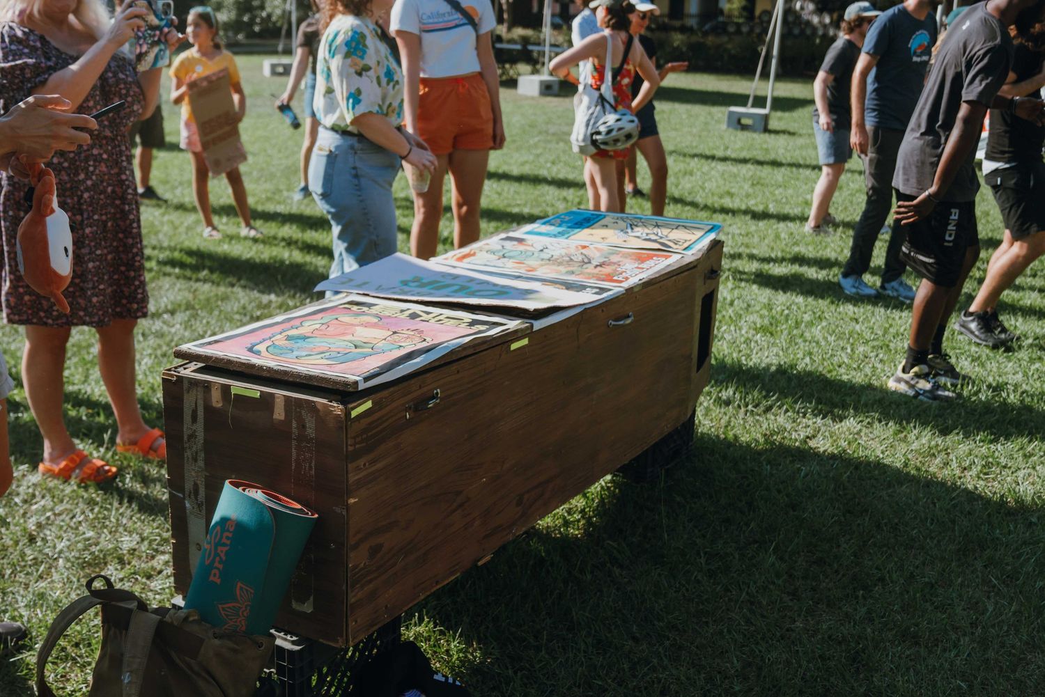 Wooden vendor booth displaying colorful artwork prints at an outdoor festival on green grass.