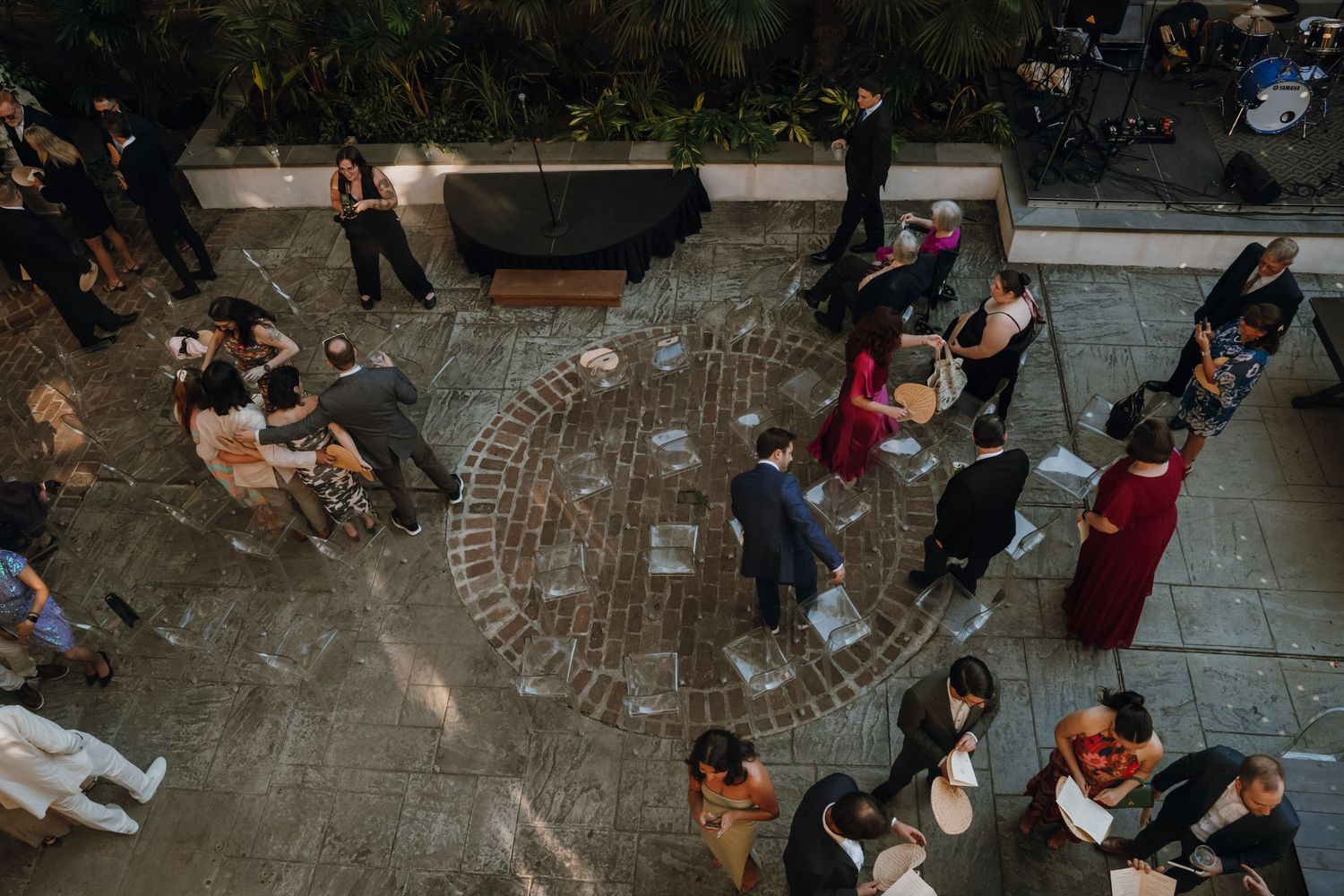 Aerial view of wedding cocktail hour guests mingling on an outdoor brick patio.