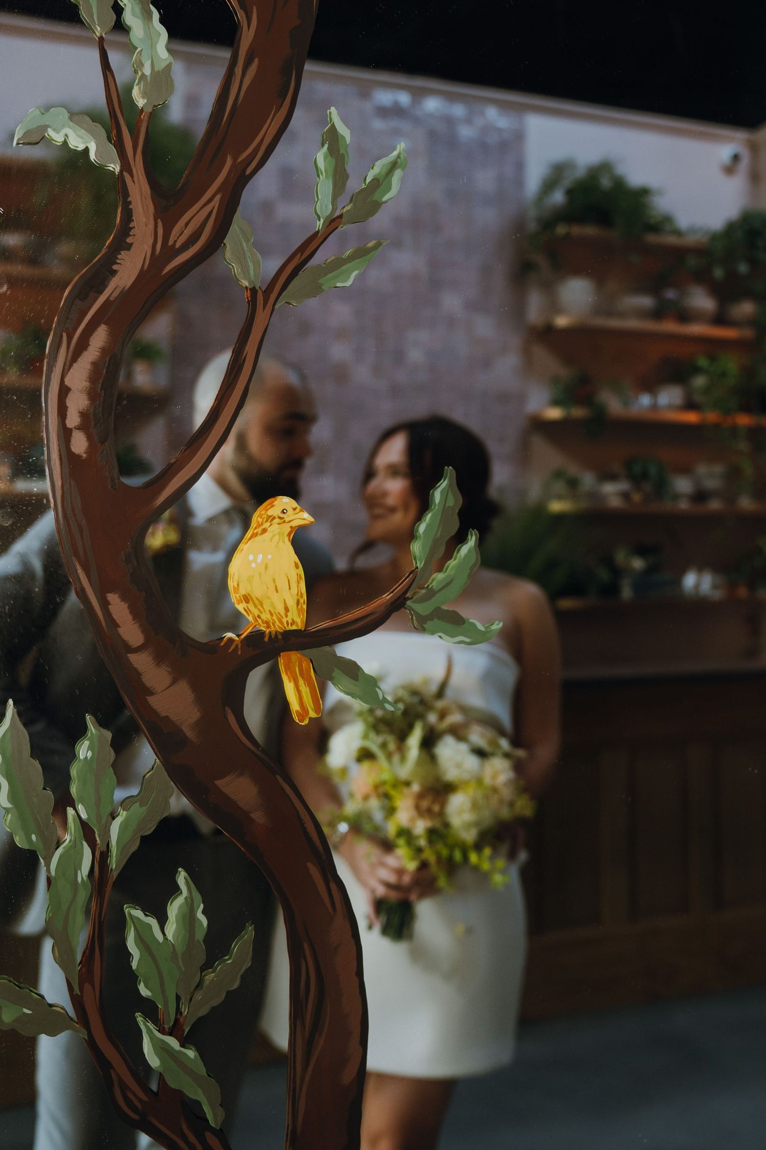 Yellow bird decoration on artistic tree sculpture with blurred bride and groom in background at wedding. New Orleans, Louisiana, Mississippi