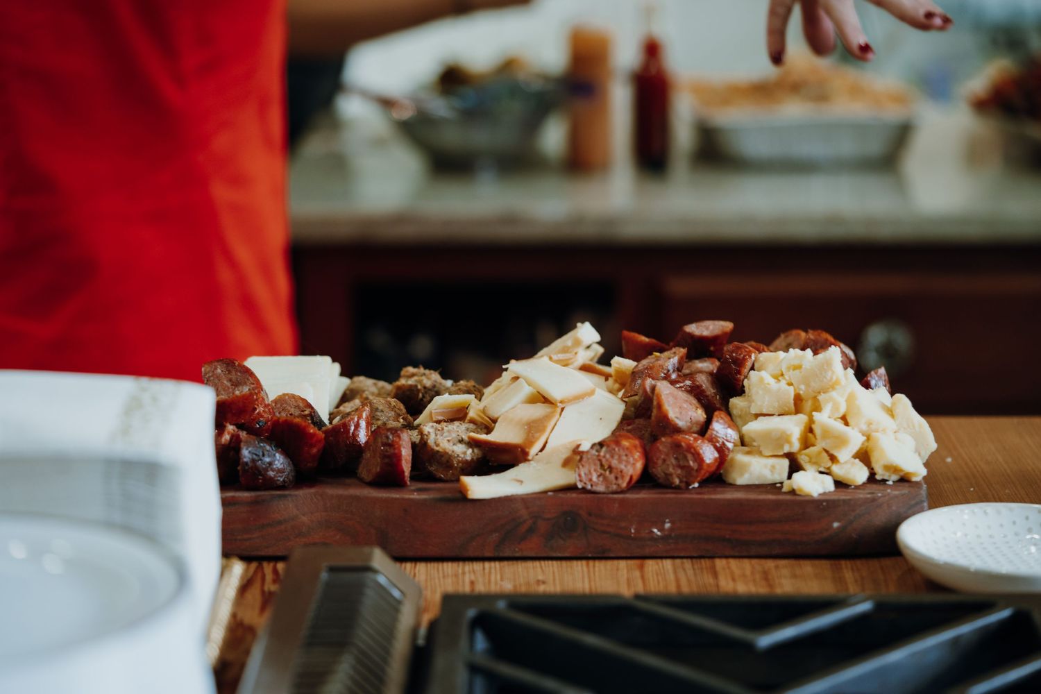 Rustic wooden charcuterie board with assorted meats and cheeses on a kitchen counter.