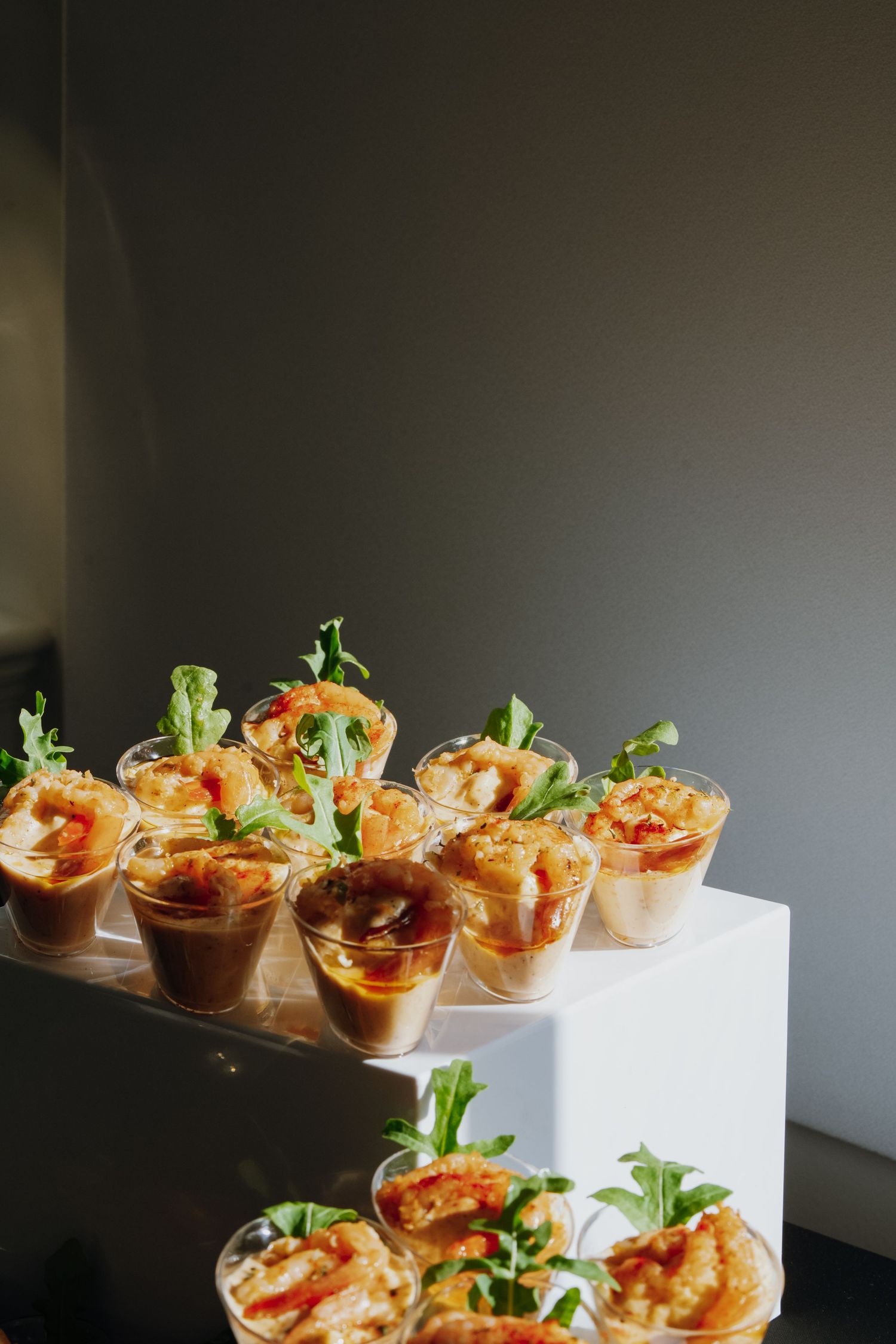 Elegant appetizers with shrimp and arugula served in clear cups on tiered display.
