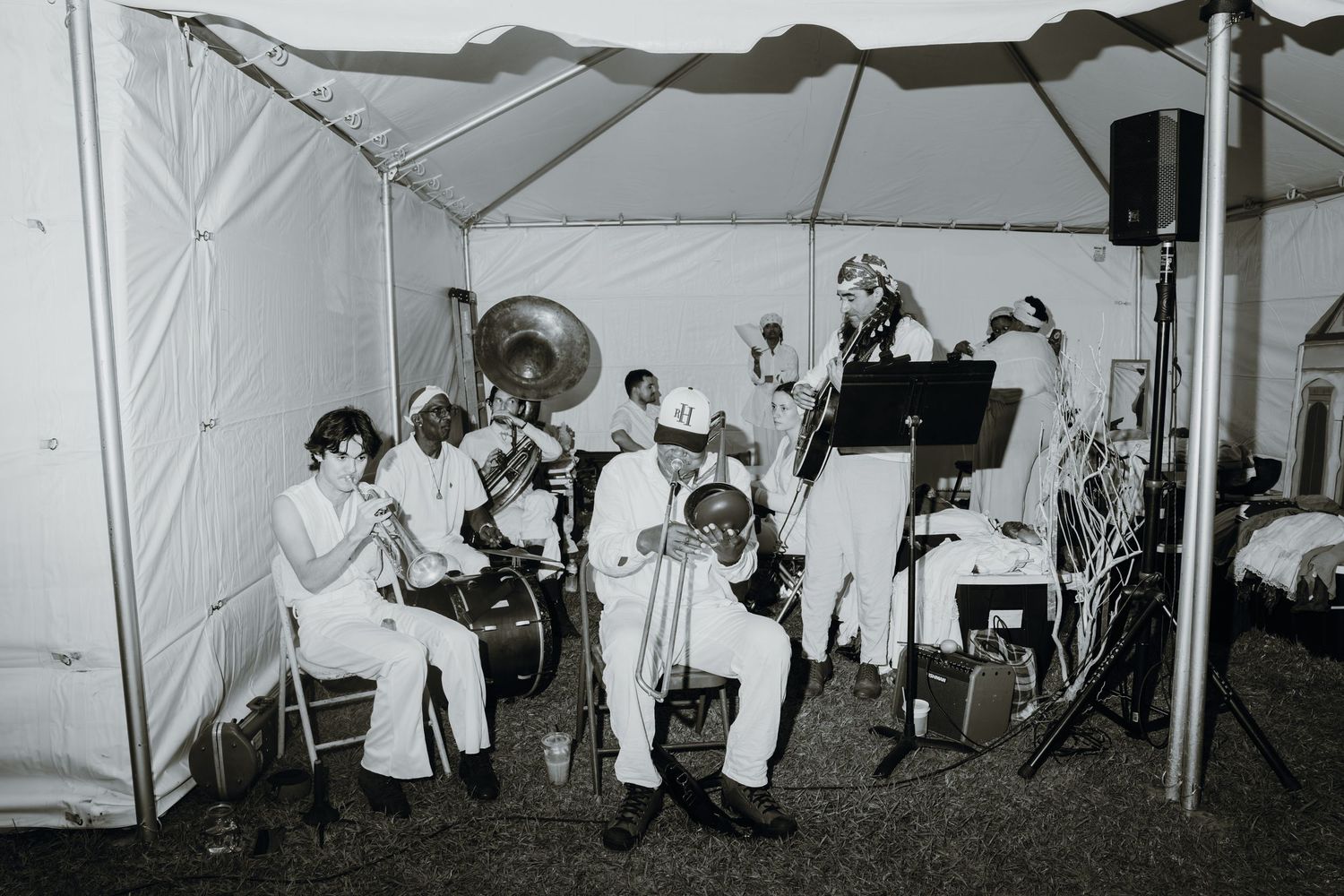Black and white photo of a jazz band in white suits performing under a tent.