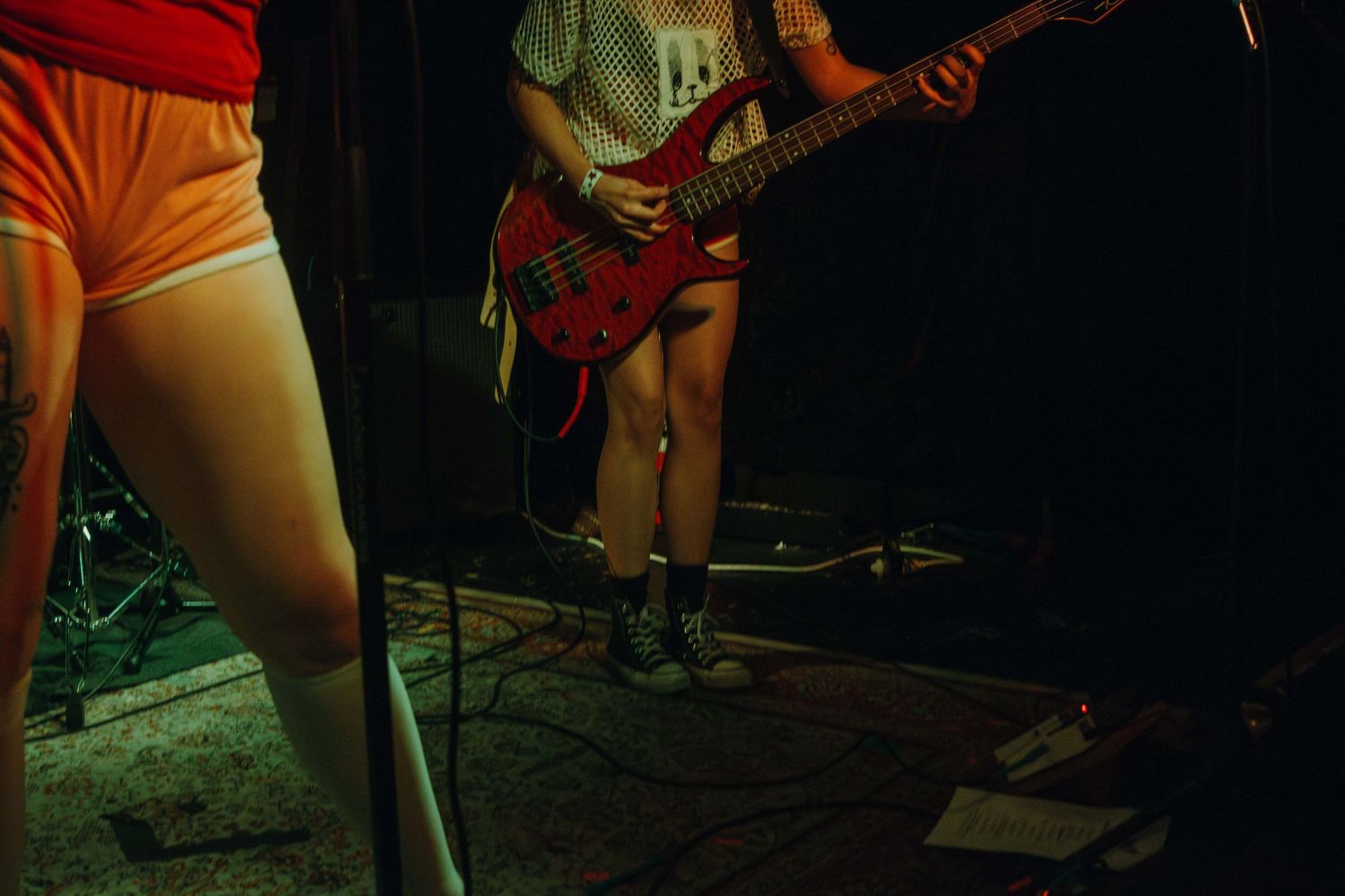 Musicians performing on stage under warm red lighting at a live music venue.