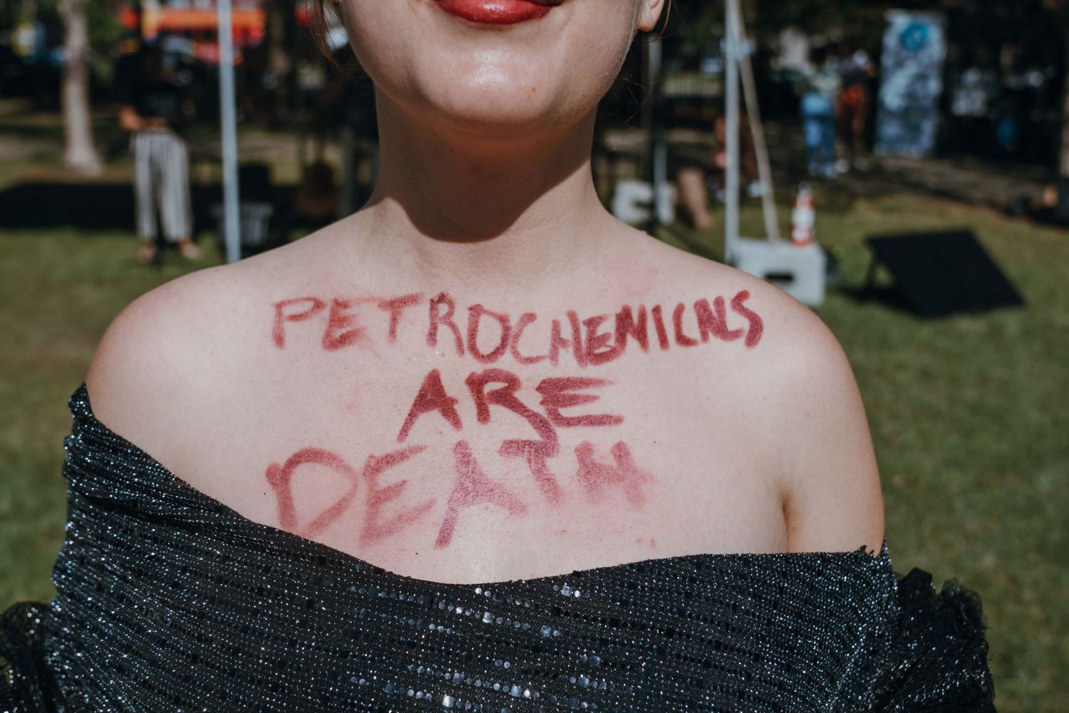 Activist with Petrochemicals Are Death written in red letters across her chest at a protest.