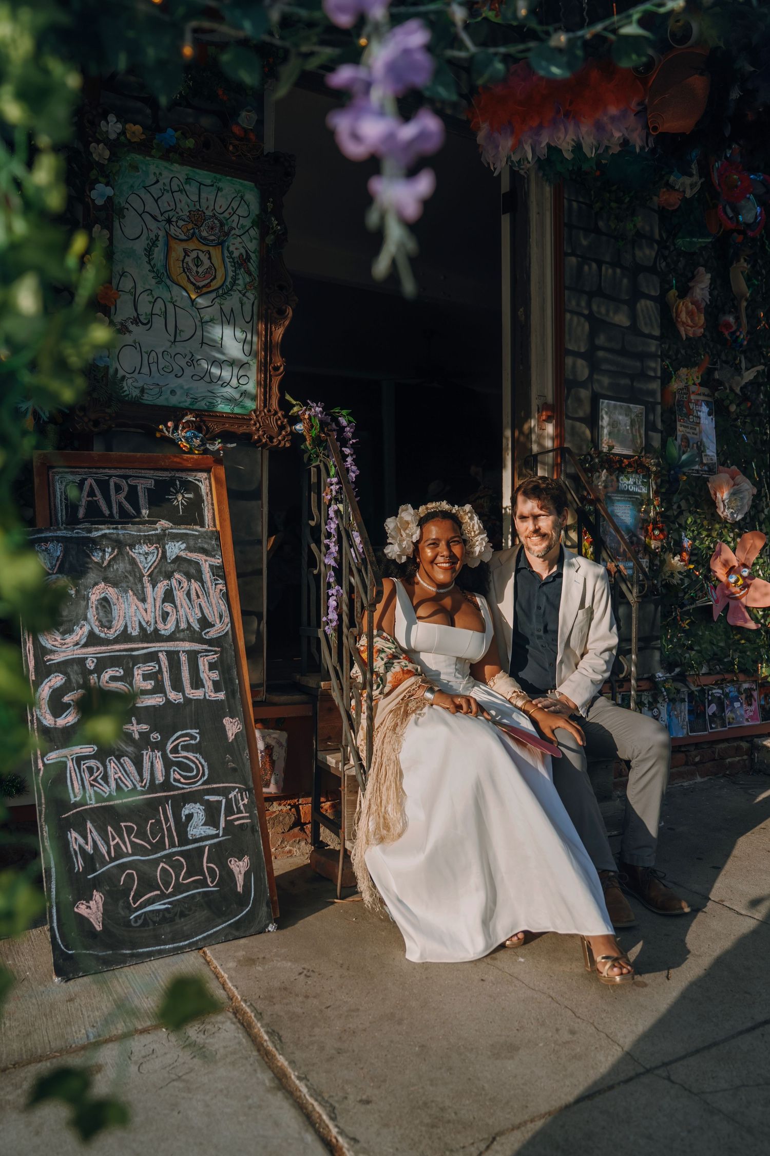Newlyweds Giselle and Travis pose by a congratulations chalkboard sign on March 27, 2026.